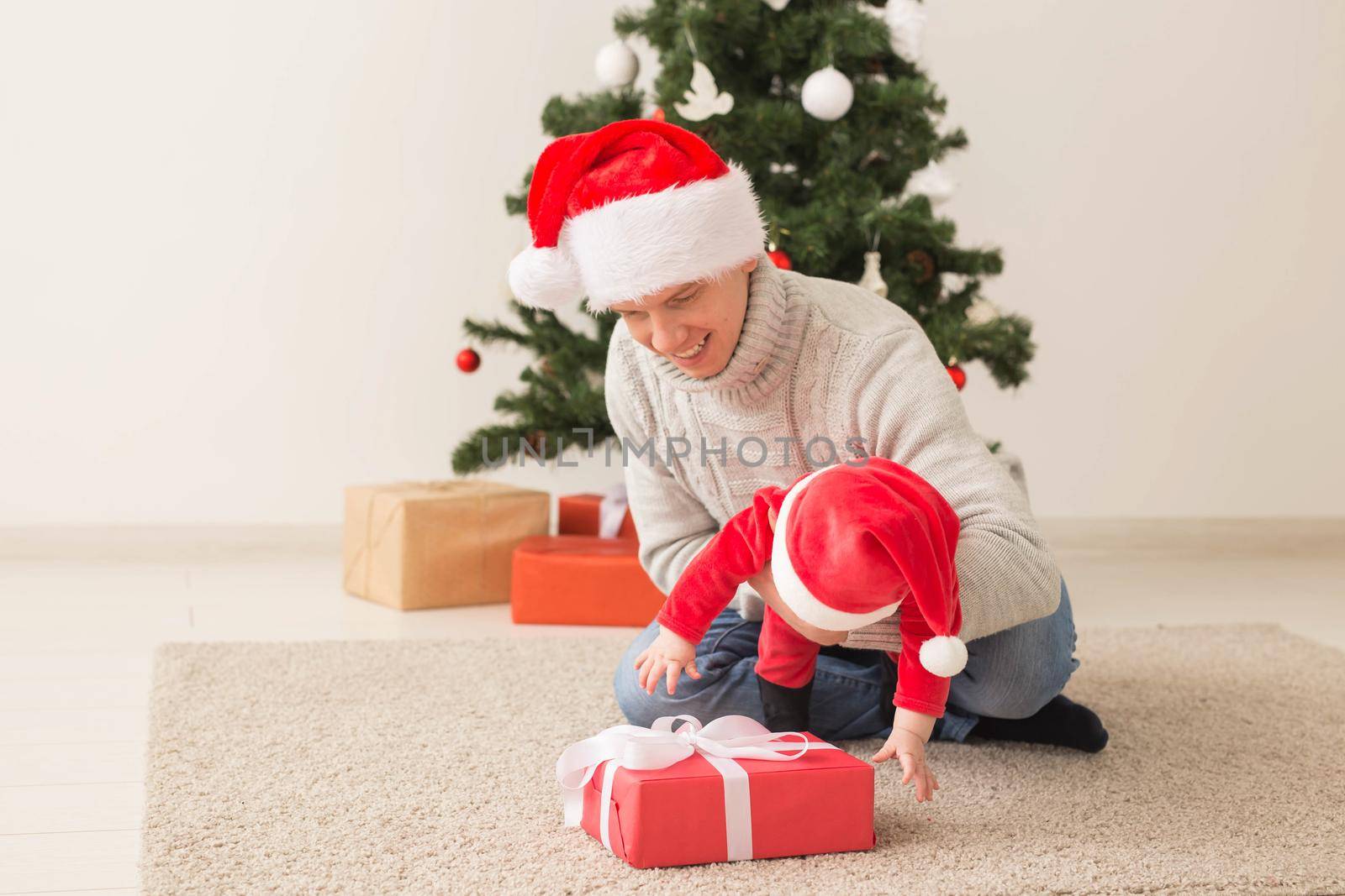 Father with his baby boy wearing Santa hats celebrating Christmas
