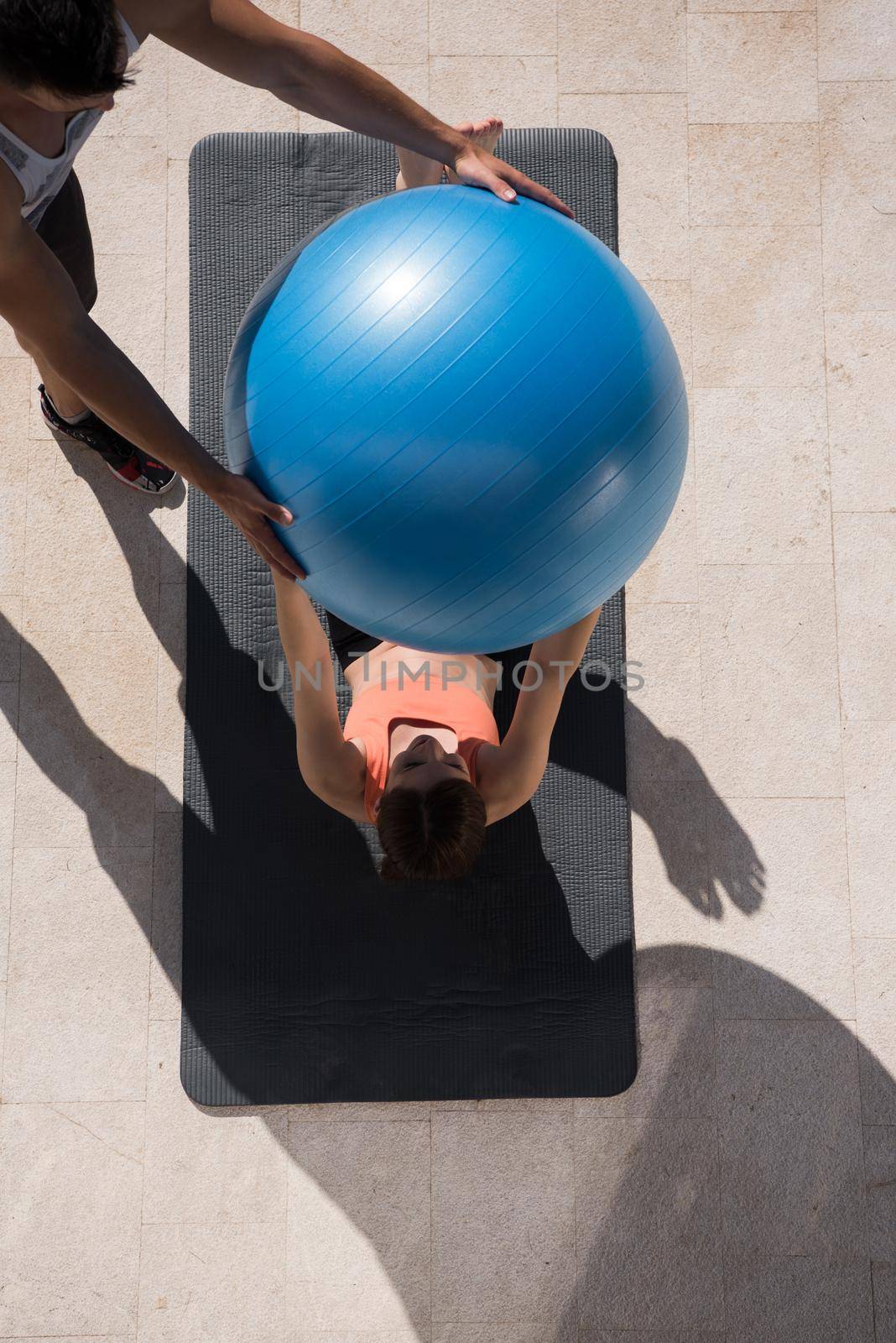 young beautiful woman and personal trainer doing exercise with pilates ball in front of her luxury home