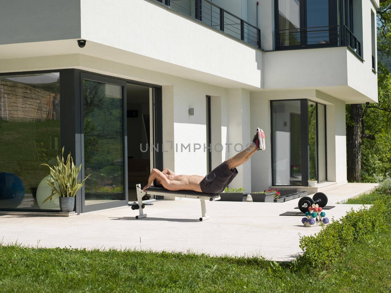 young handsome man doing morning exercises in front of his luxury home villa