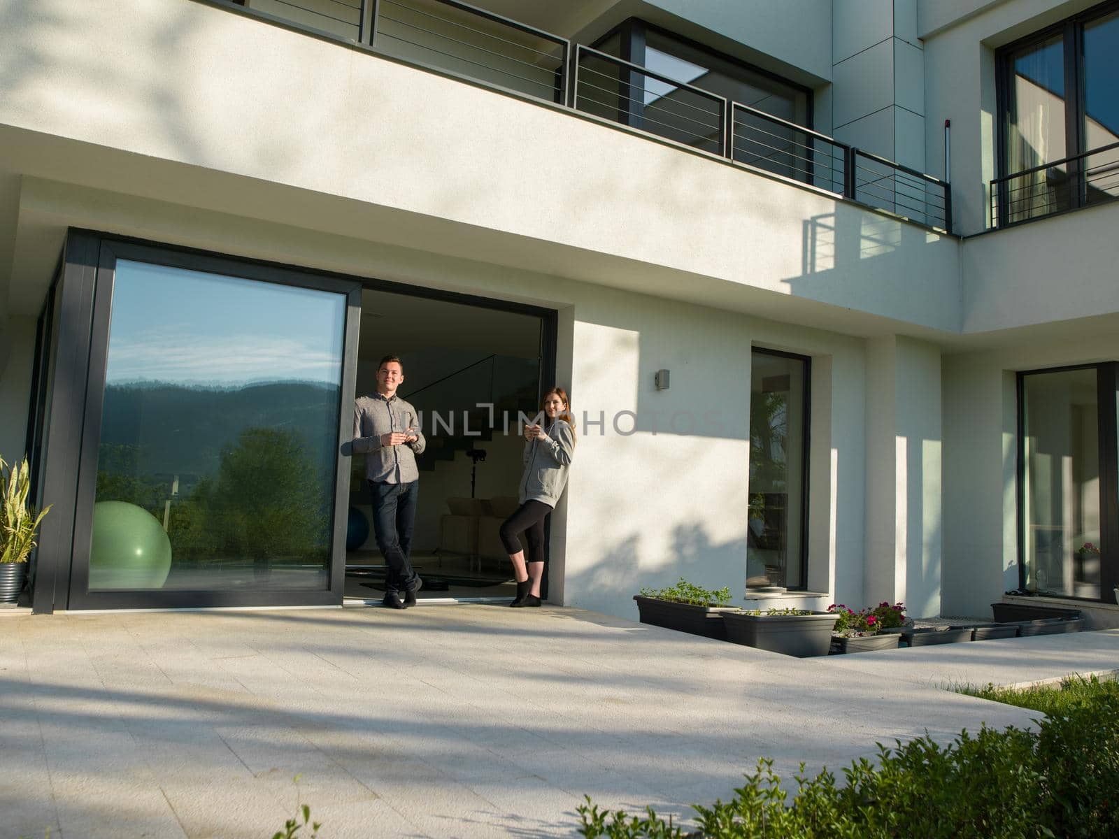 young beautiful handsome couple enjoying morning coffee on the door of their luxury home villa