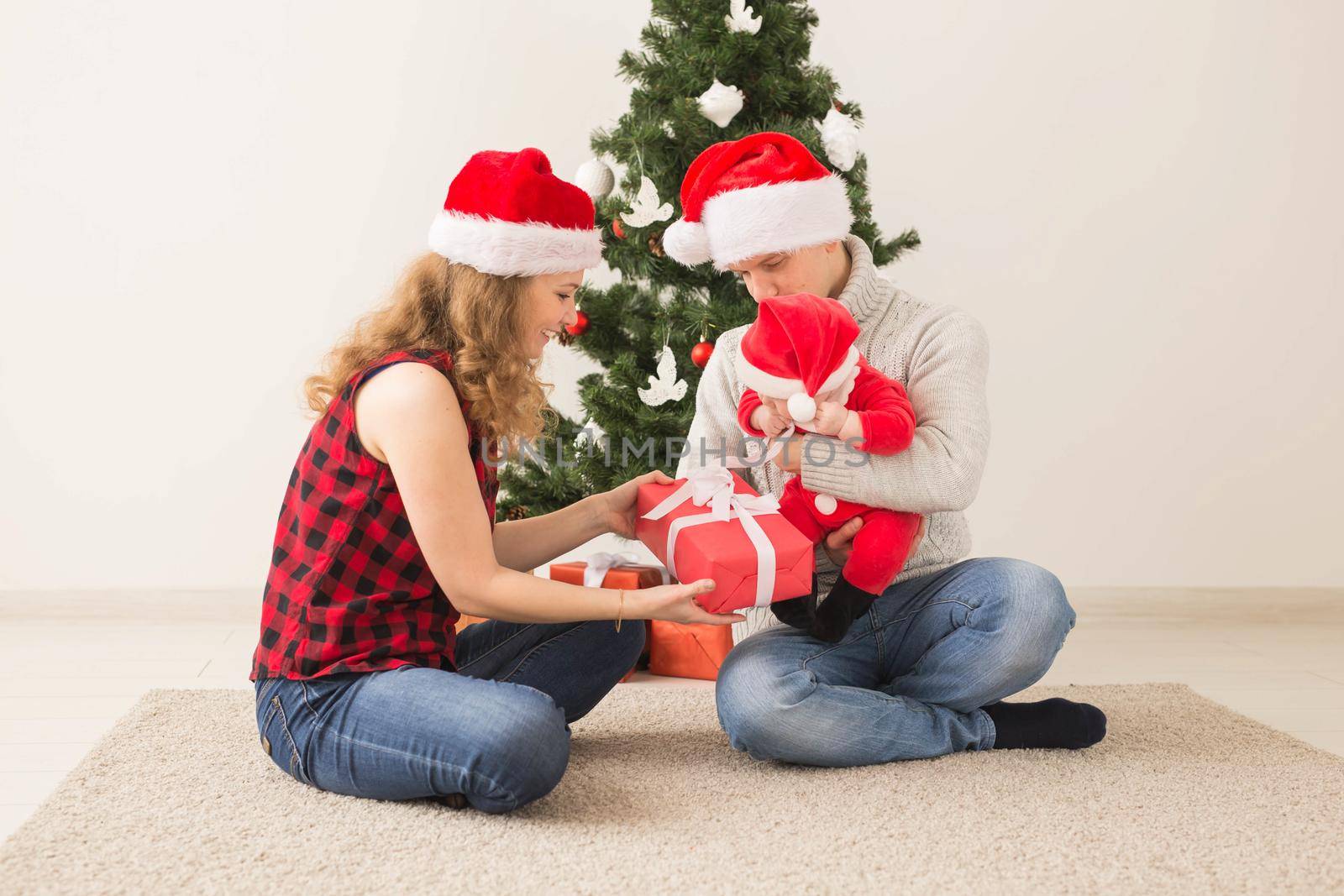 Happy couple with baby celebrating Christmas together at home