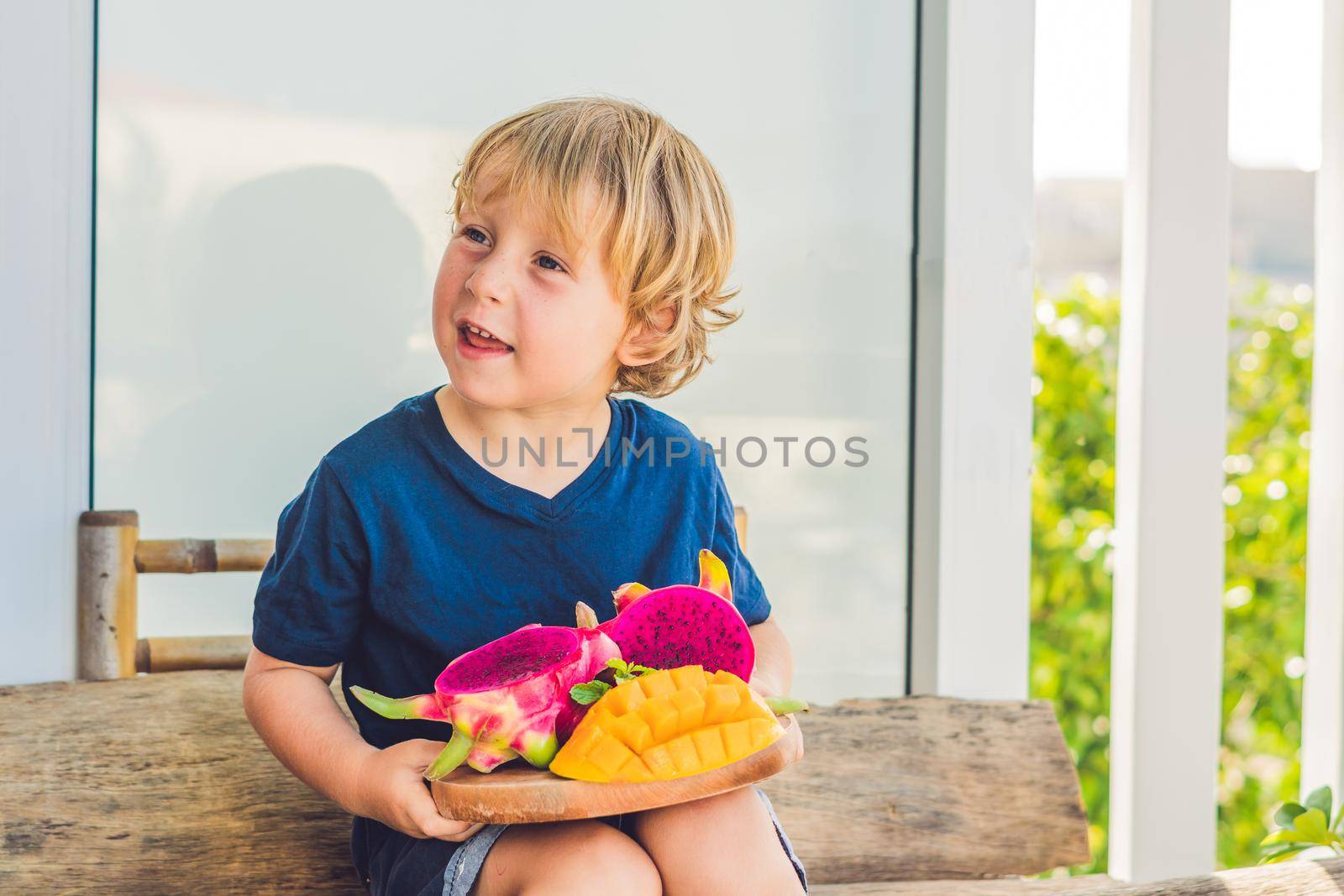 Diced dragon fruit and mango in the hands of the boy by galitskaya