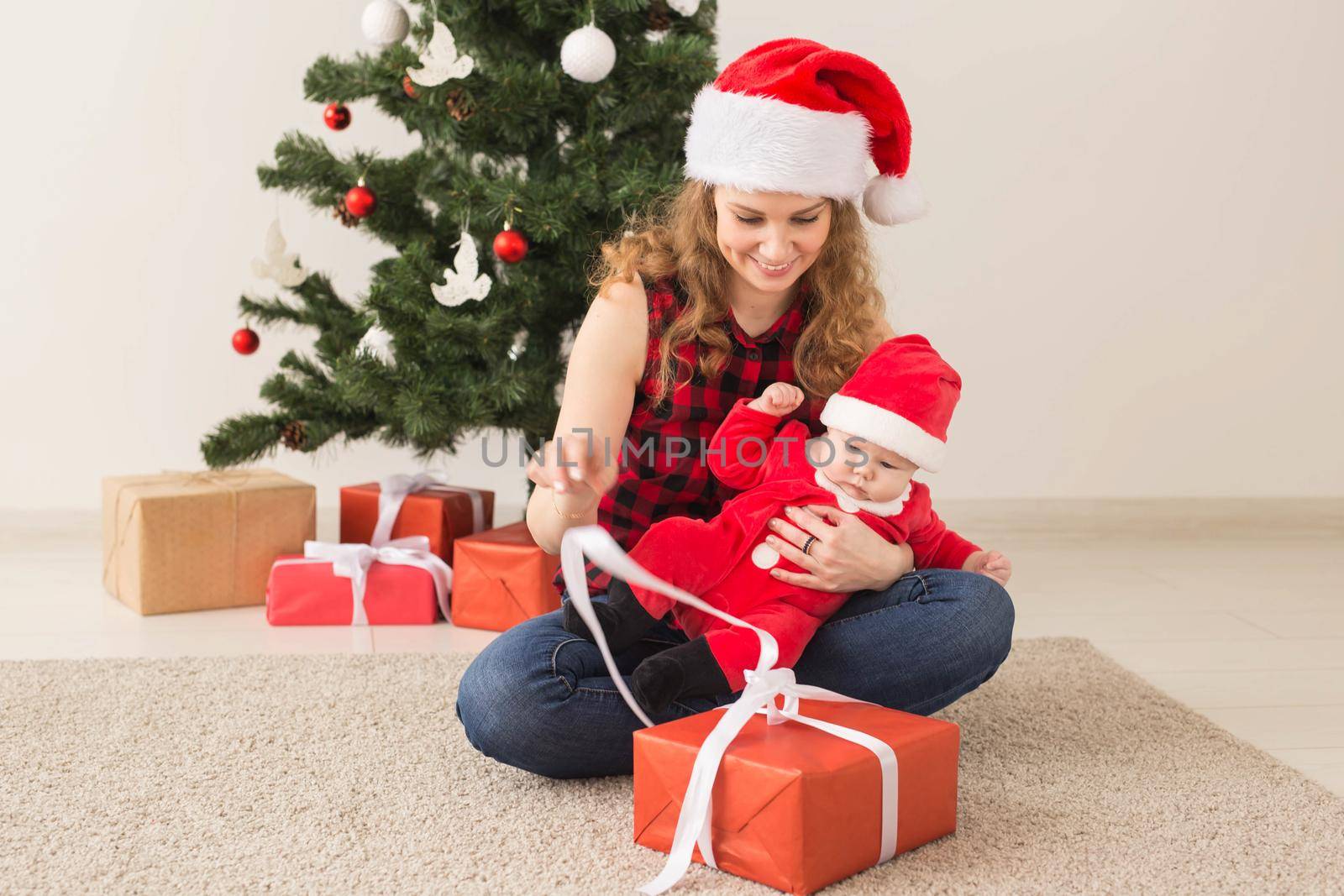 Family, childhood and Christmas concept - Portrait of happy mother and adorable baby in suit of Santa.