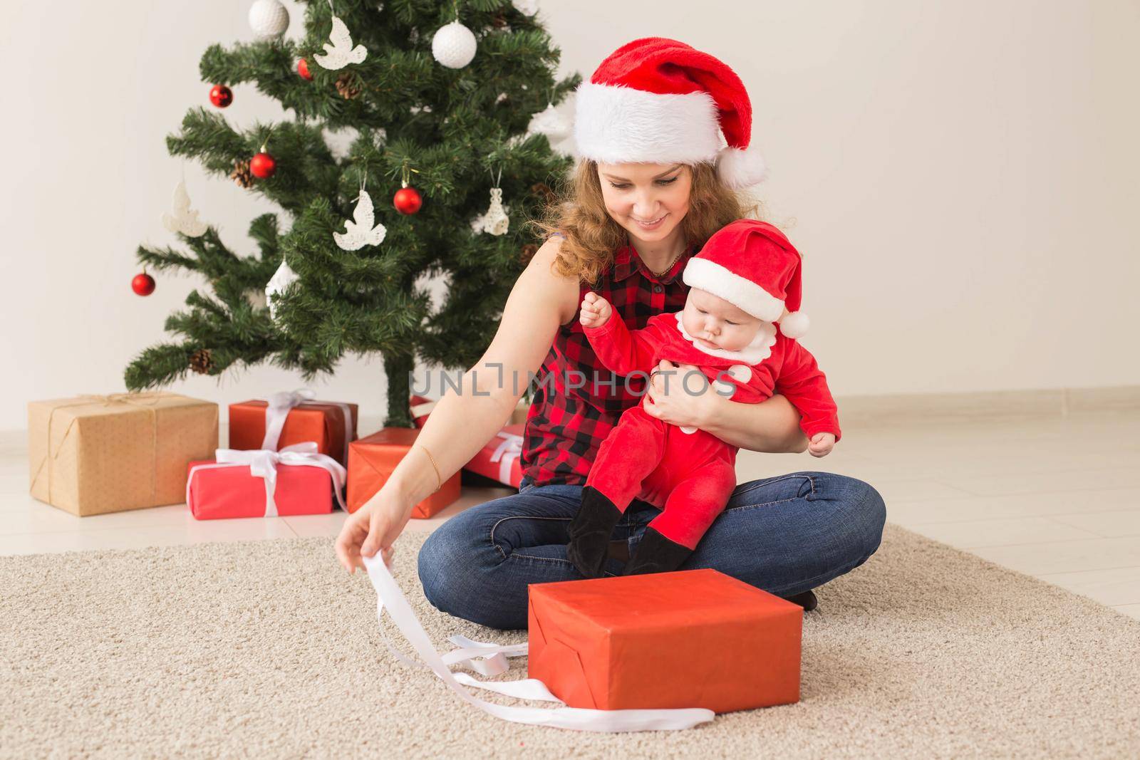 Family, childhood and Christmas concept - Portrait of happy mother and adorable baby in suit of Santa.
