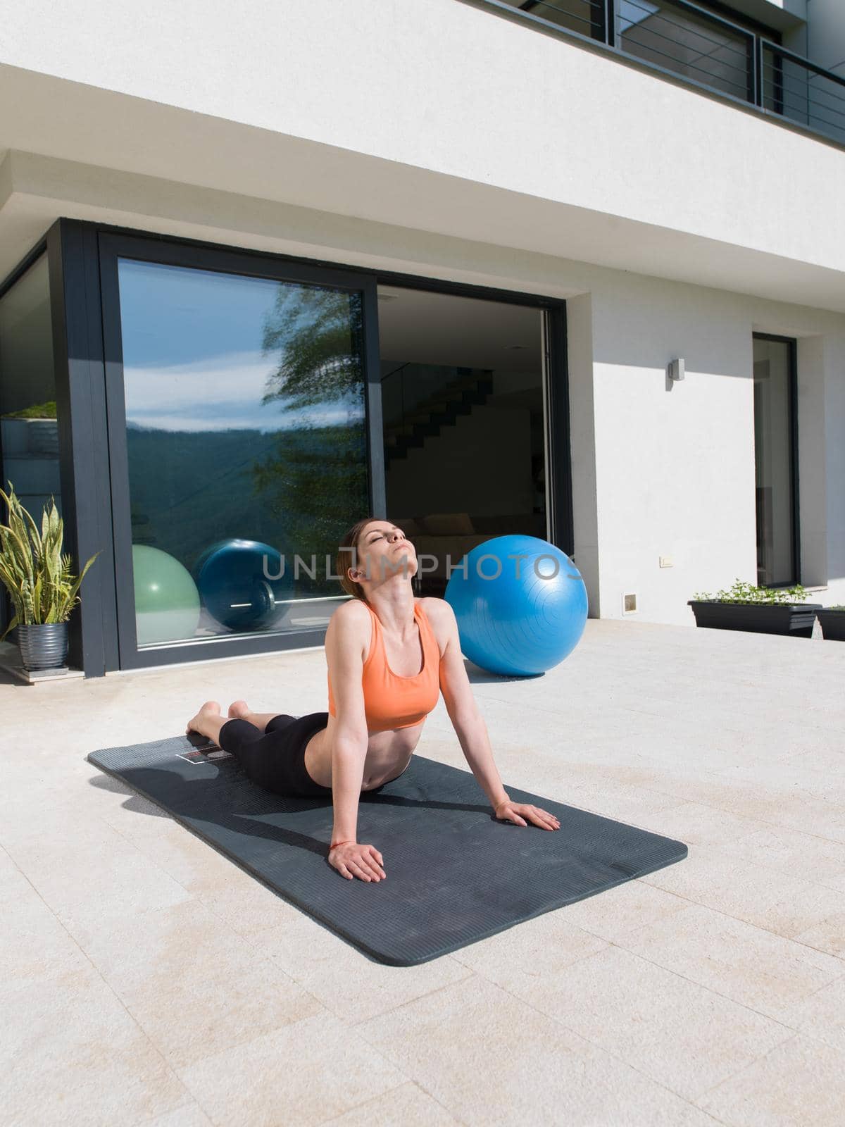 young handsome woman doing morning yoga exercises in front of her luxury home villa