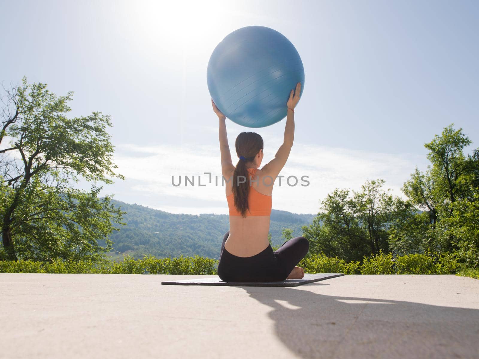 young beautiful woman doing exercise with pilates ball in front of her luxury home villa