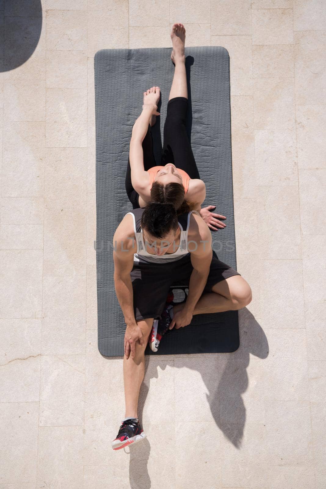 young handsome woman with personal trainer doing morning yoga exercises in front of her luxury home villa top view