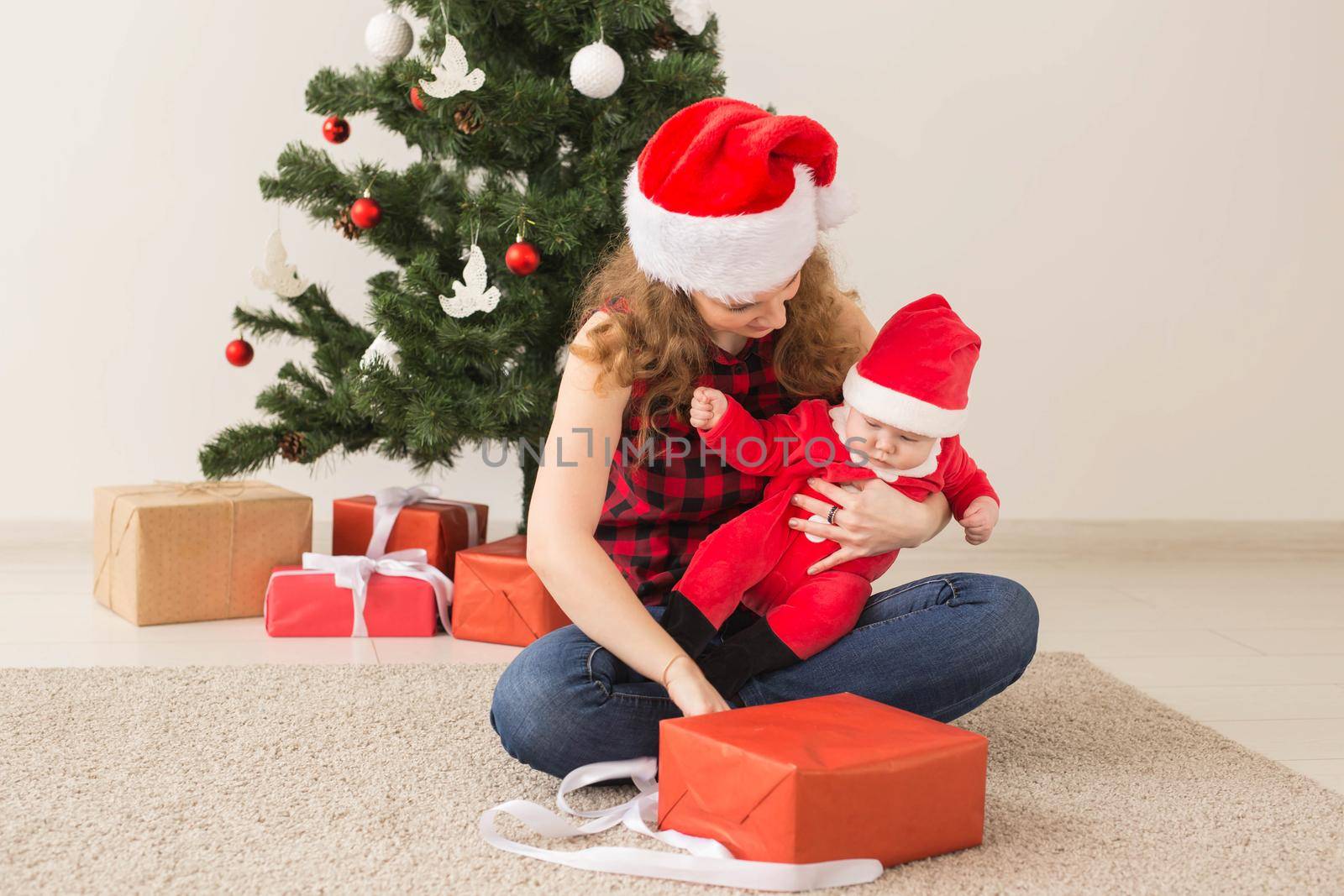 Family, childhood and Christmas concept - Portrait of happy mother and adorable baby in suit of Santa.