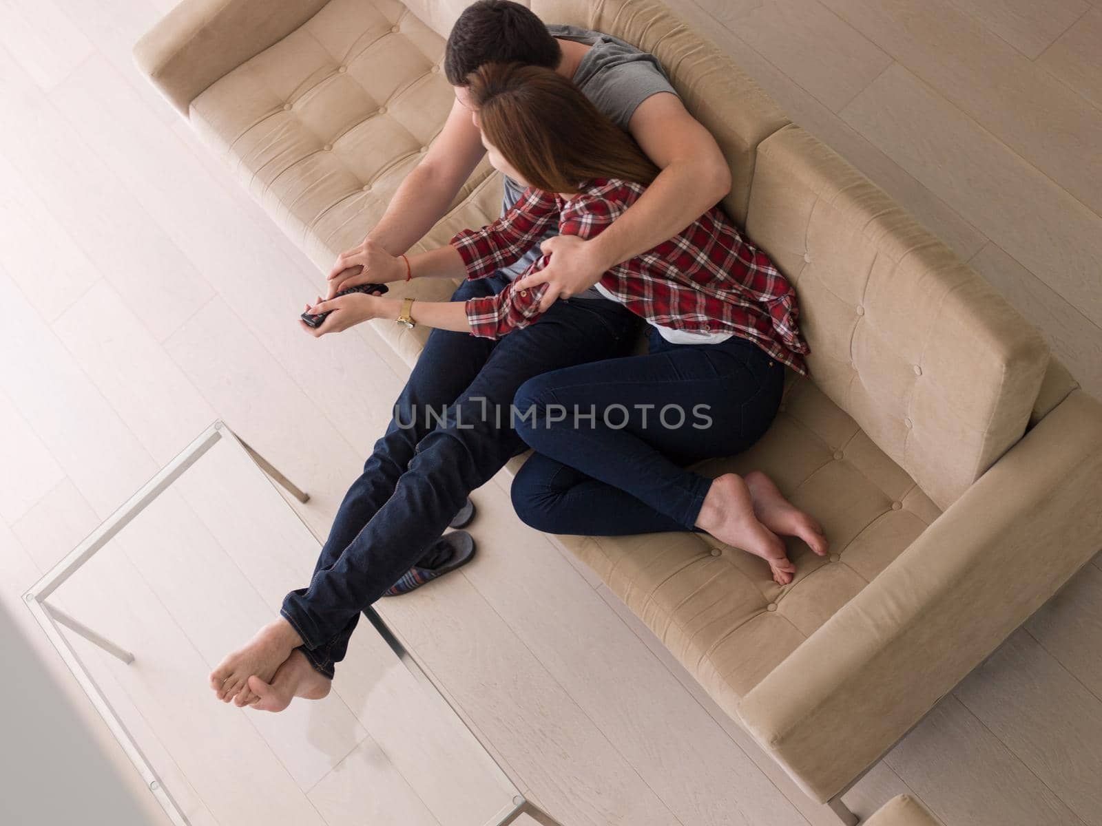 Young couple on the sofa watching television together in their luxury home