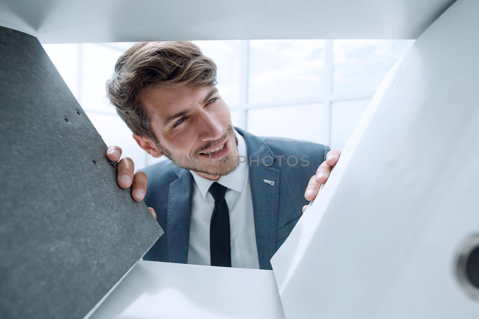 pensive man looks at documents in a closet in the office