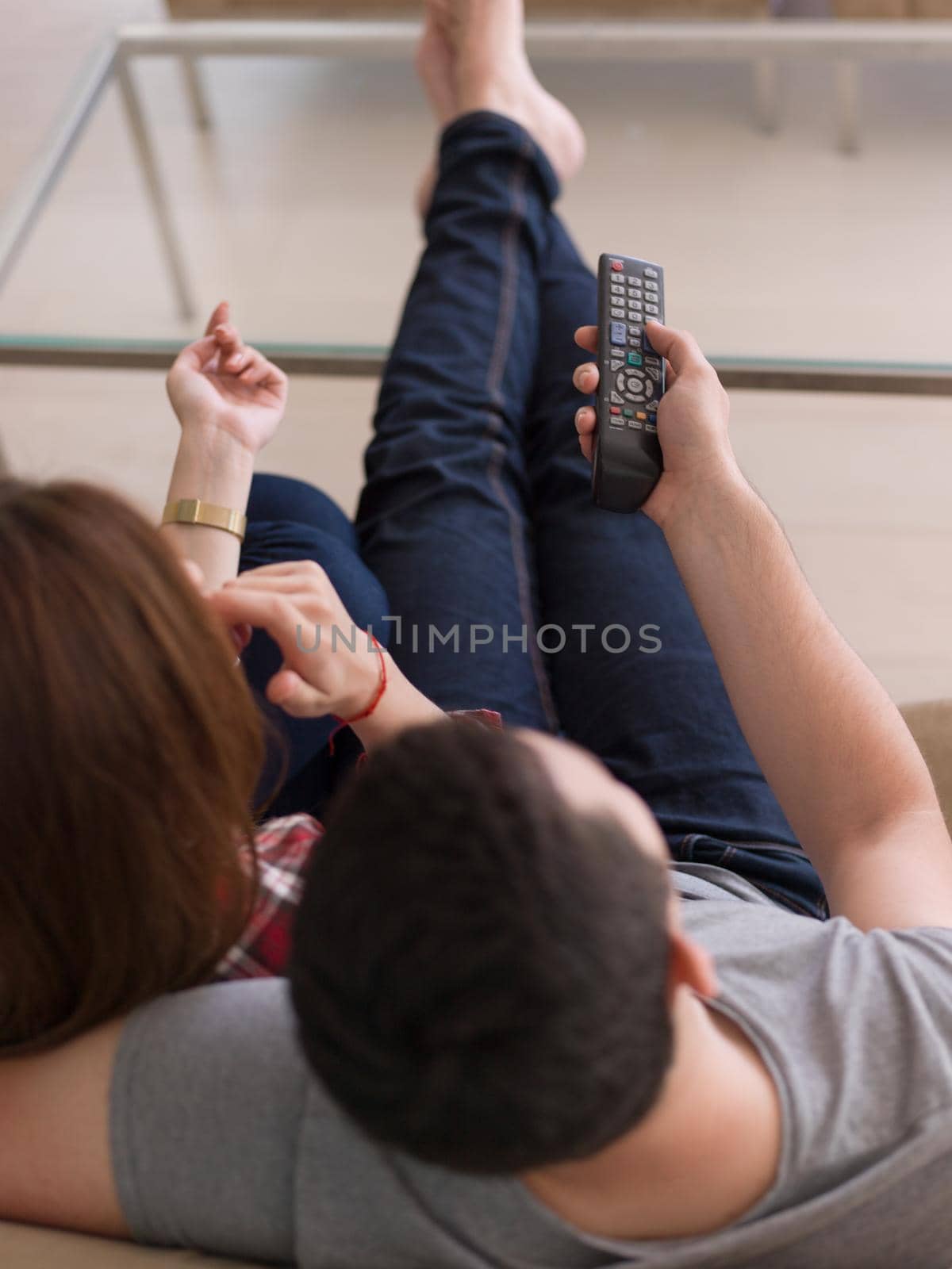 Young couple on the sofa watching television together in their luxury home