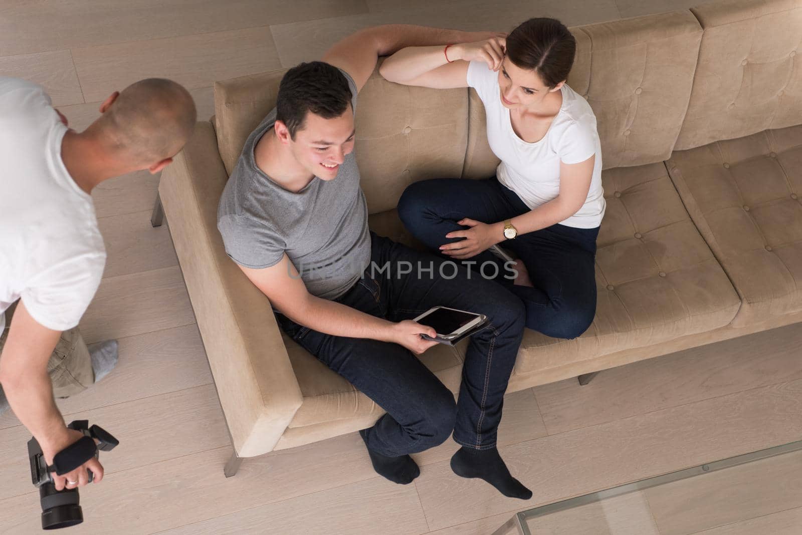 Young couple relaxing at luxurious home with tablet computers reading in the living room on the sofa couch.