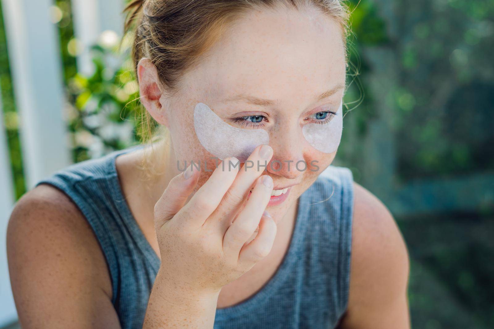 Portrait of Beauty Red-haired woman with eye patches showing an effect of perfect skin. Spa Girl.