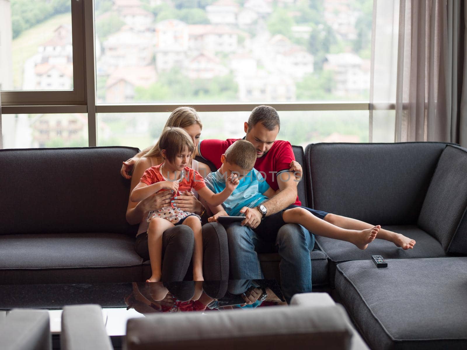 Happy Young Family Playing Together with tablet at home sitting on the sofa