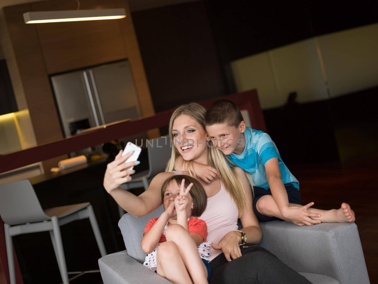 Happy family siting on sofa and using cell phone for video call  at home