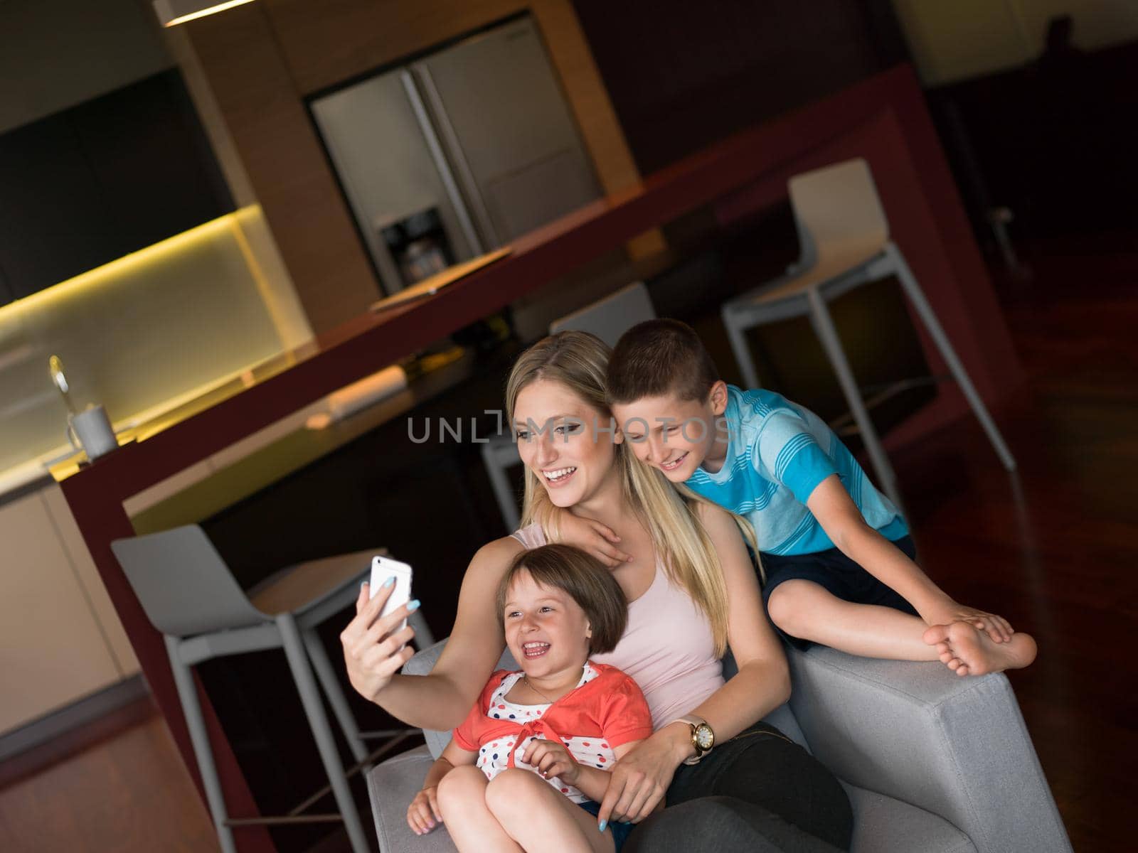 Happy family siting on sofa and using cell phone for video call  at home