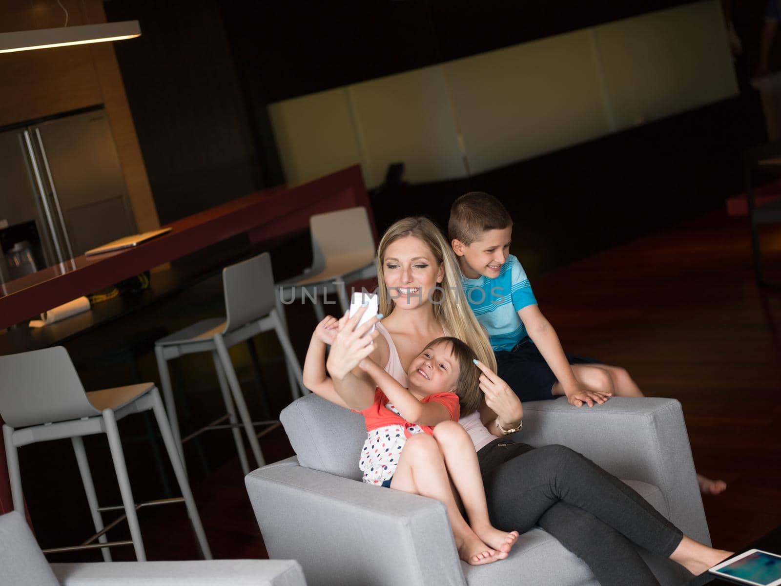 Happy family siting on sofa and using cell phone for video call  at home