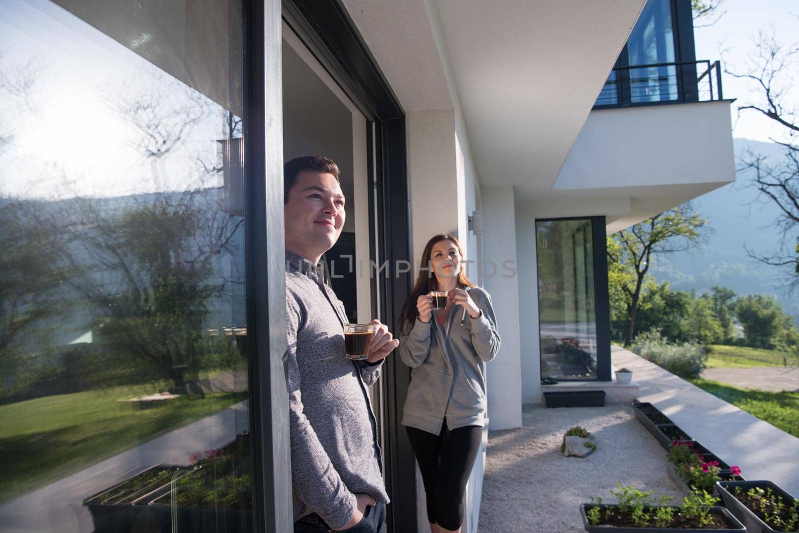 young beautiful handsome couple enjoying morning coffee on the door of their luxury home villa