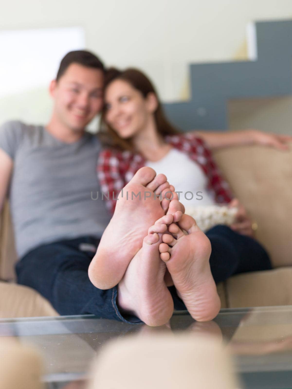 young handsome couple enjoying free time watching television with popcorn in their luxury home villa