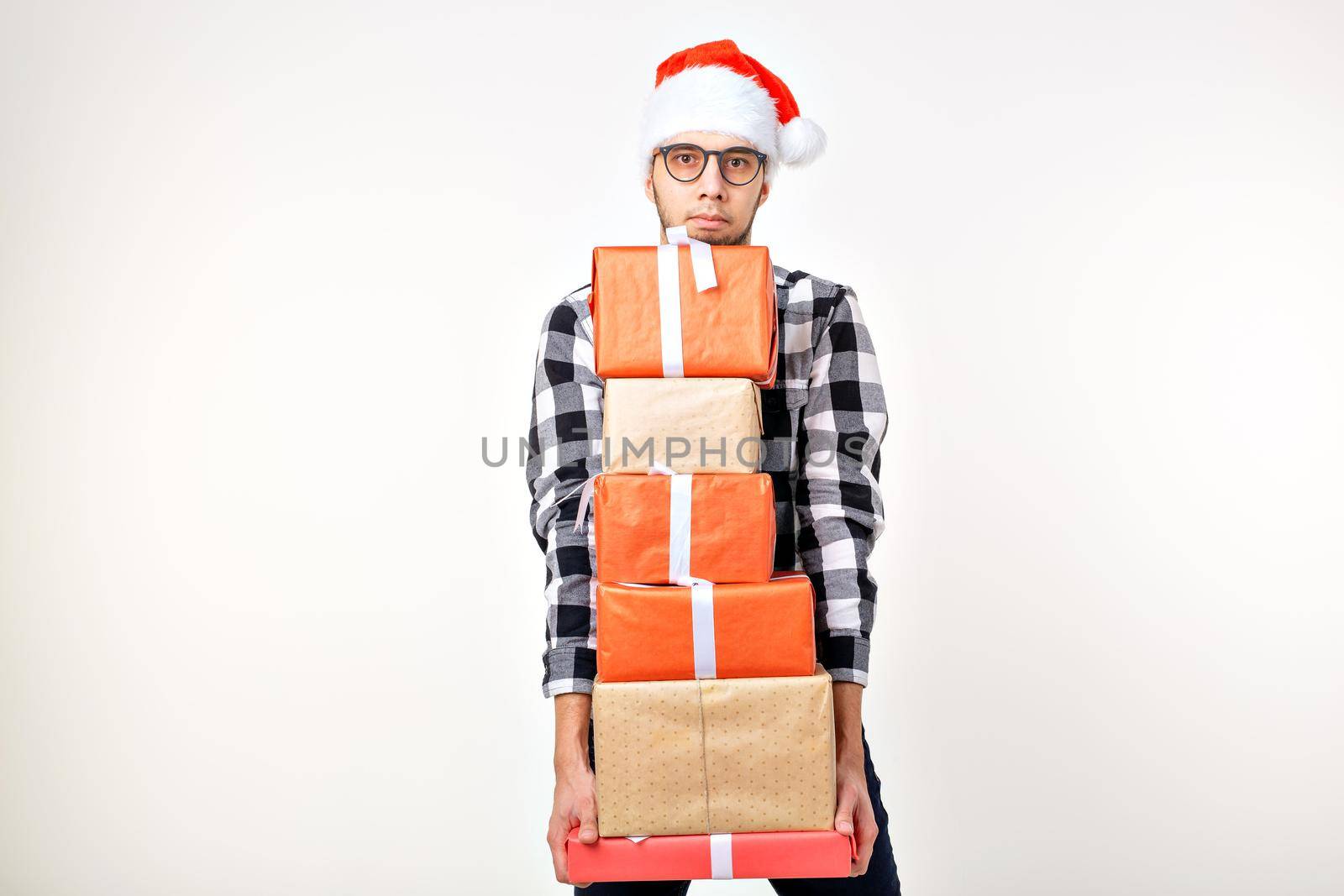 Holidays and presents concept - Funny man in Christmas hat holding many gift boxes on white background with copy space by Satura86