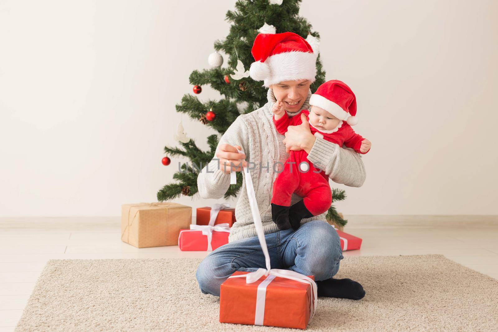 Father with his baby boy wearing Santa hats celebrating Christmas. by Satura86