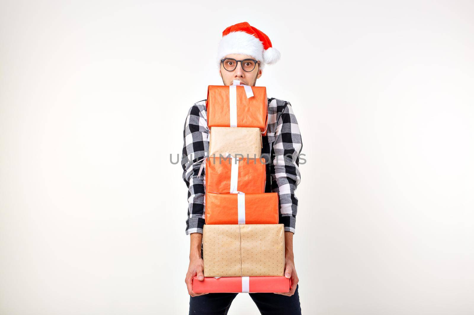 Holidays and presents concept - Funny man in Christmas hat holding many gift boxes on white background with copyspace by Satura86