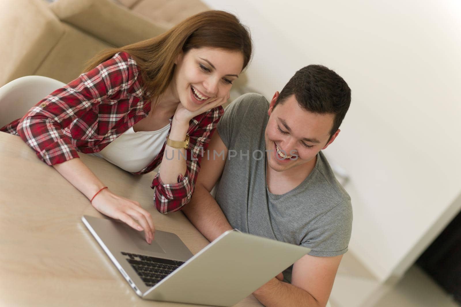 happy young couple buying online using laptop a computer and a credit card in their luxury home villa