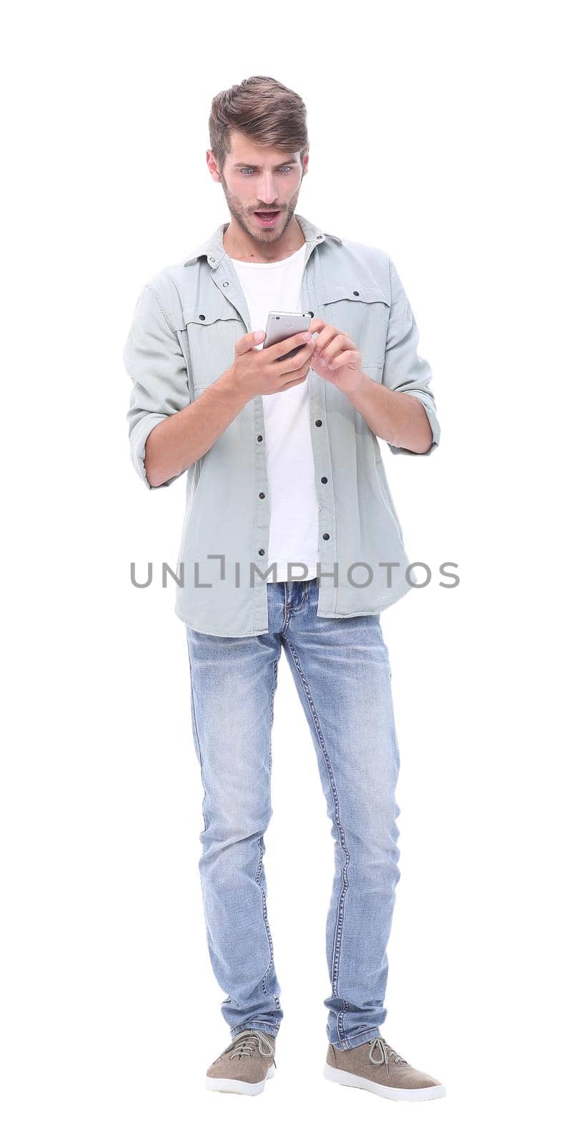 in full growth. young man typing SMS on smartphone.isolated on white background
