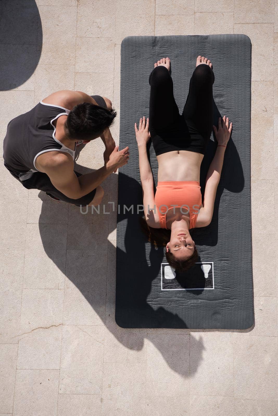 young handsome woman with personal trainer doing morning yoga exercises in front of her luxury home villa top view