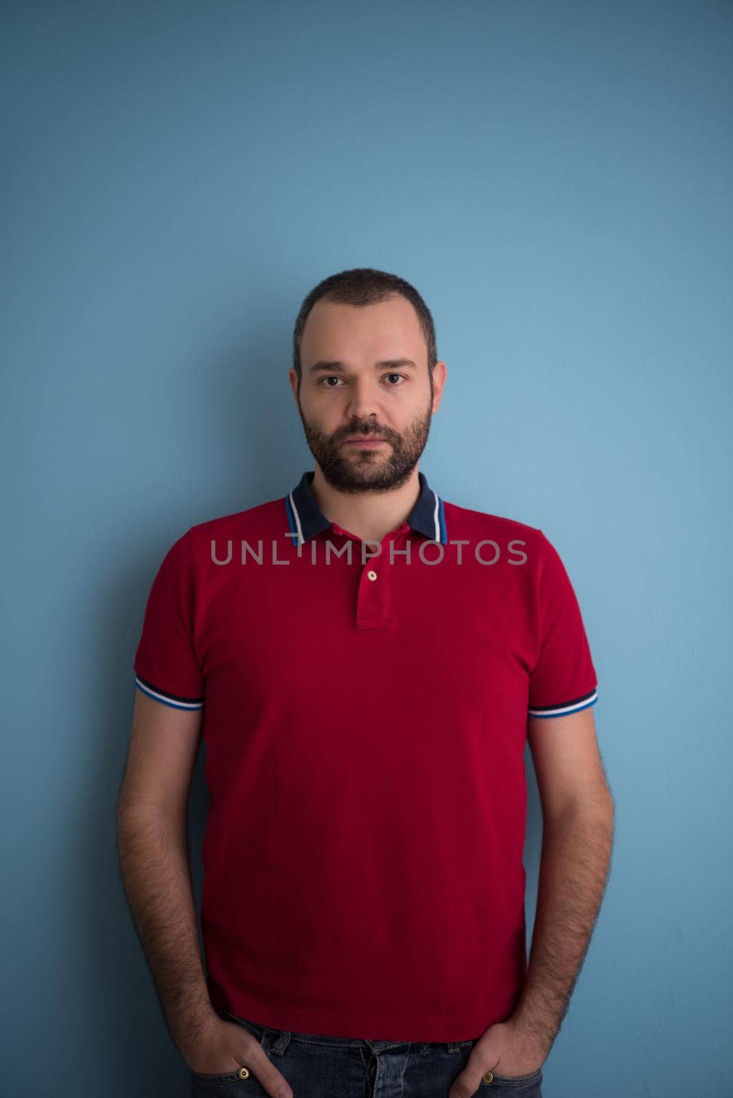 portrait of young man with hands in the pockets isolated over a blue background