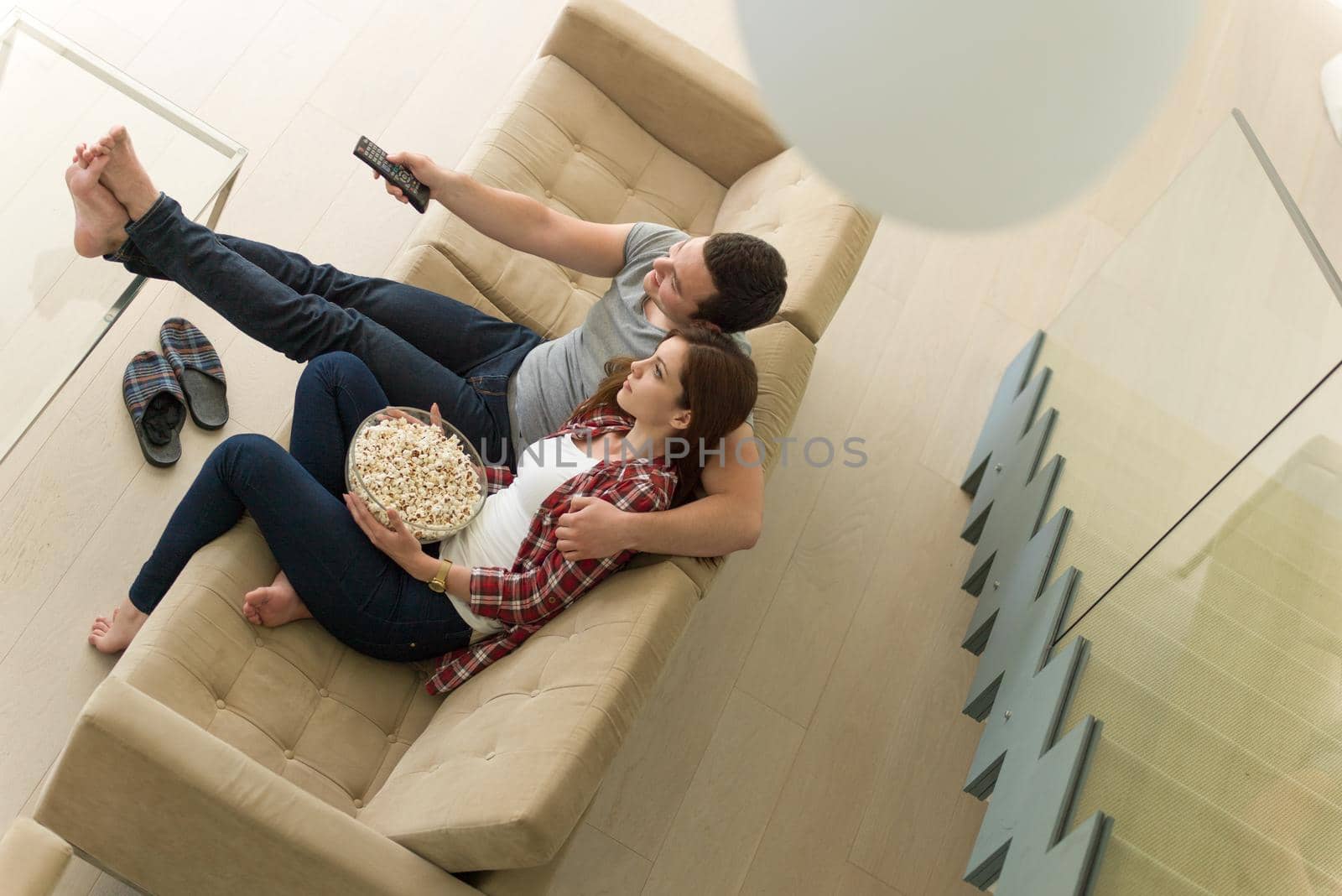 young handsome couple enjoying free time watching television with popcorn in their luxury home villa