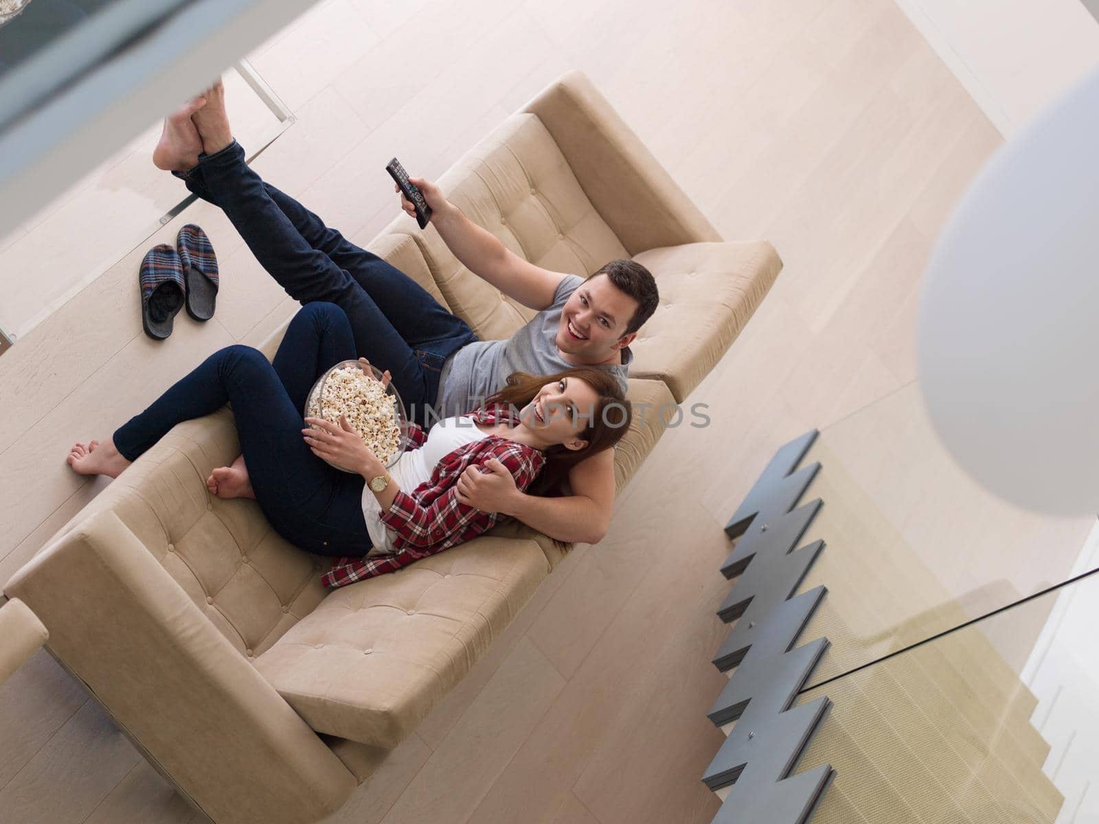 young handsome couple enjoying free time watching television with popcorn in their luxury home villa