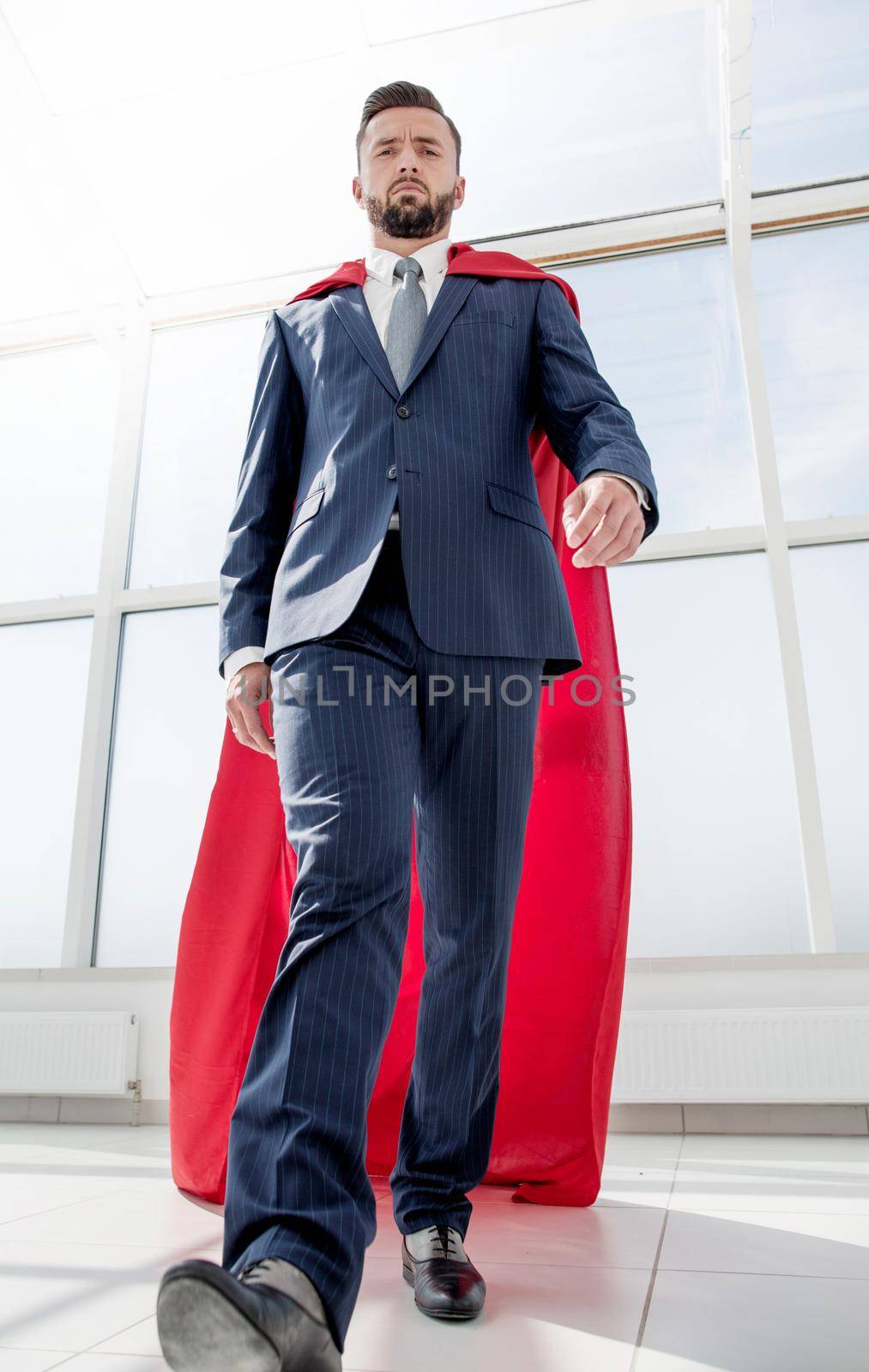 businessman in a Superman cloak standing in a bright office.photo with copy space