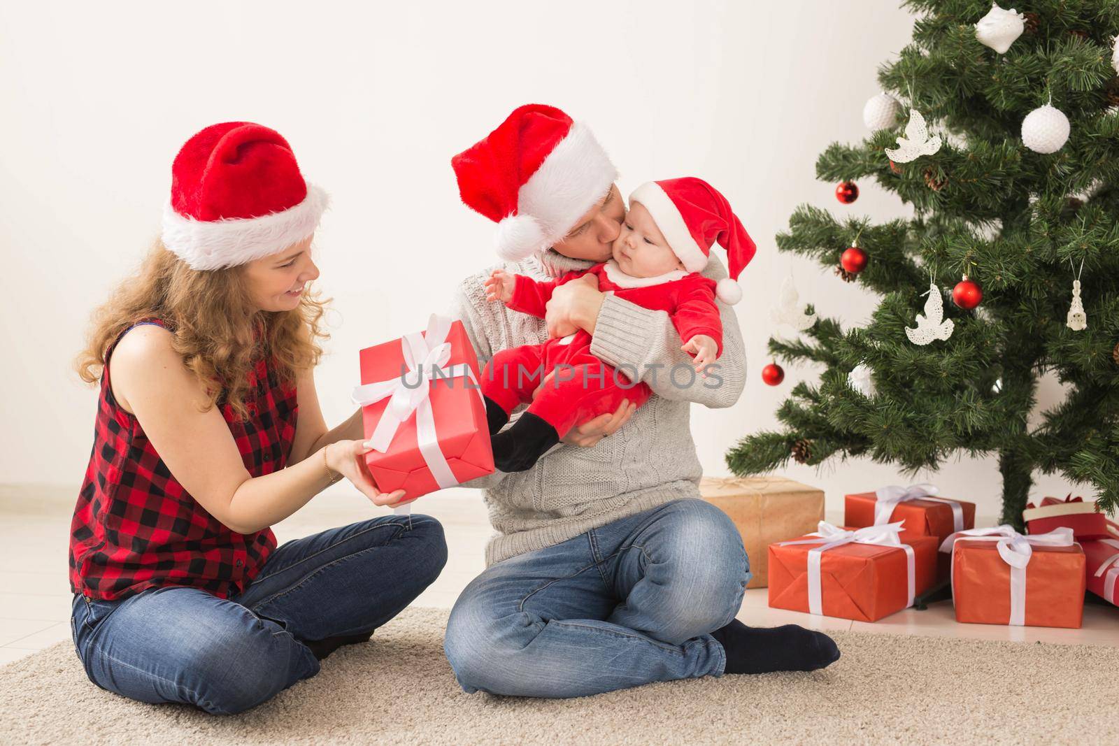 Holidays, children and family concept - Happy couple with baby celebrating Christmas together at home