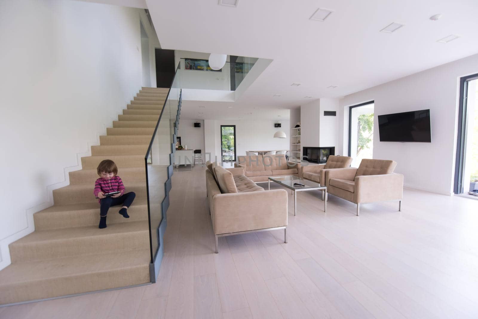 little cute girl enjoying on the stairs in a modern living room of her luxury home