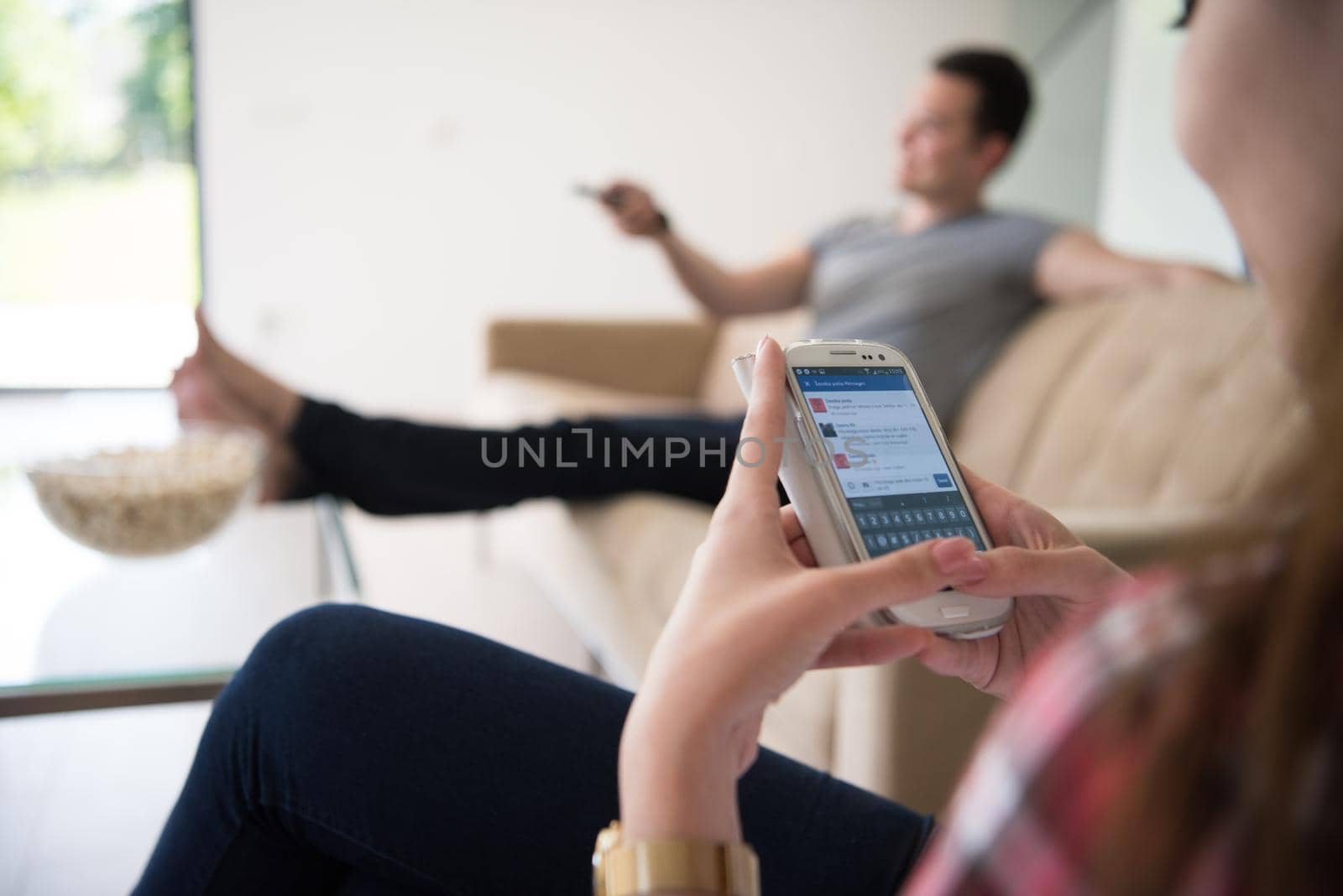 young handsome couple enjoying free time watching television with popcorn in their luxury home villa