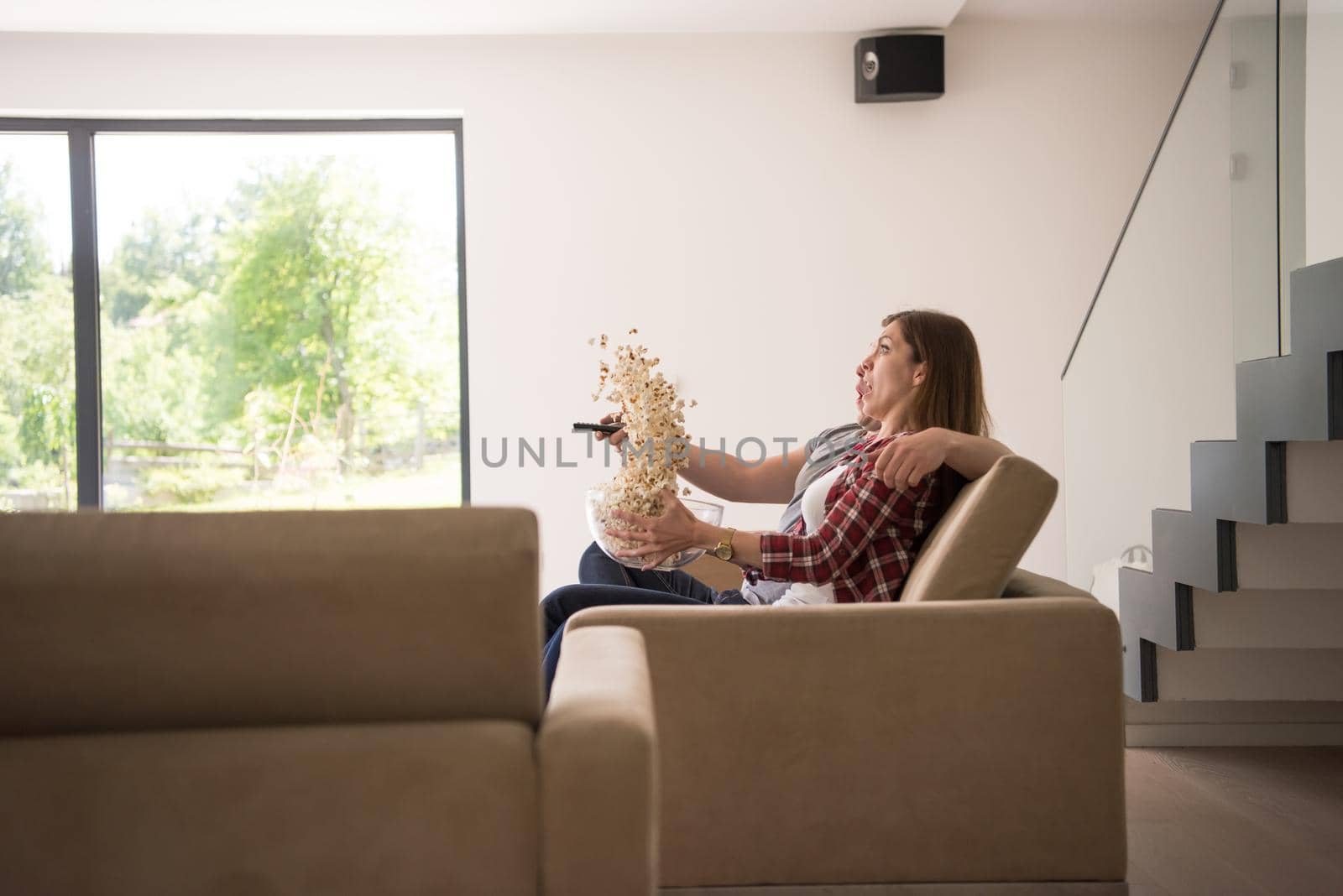 young handsome couple enjoying free time watching television with popcorn in their luxury home villa