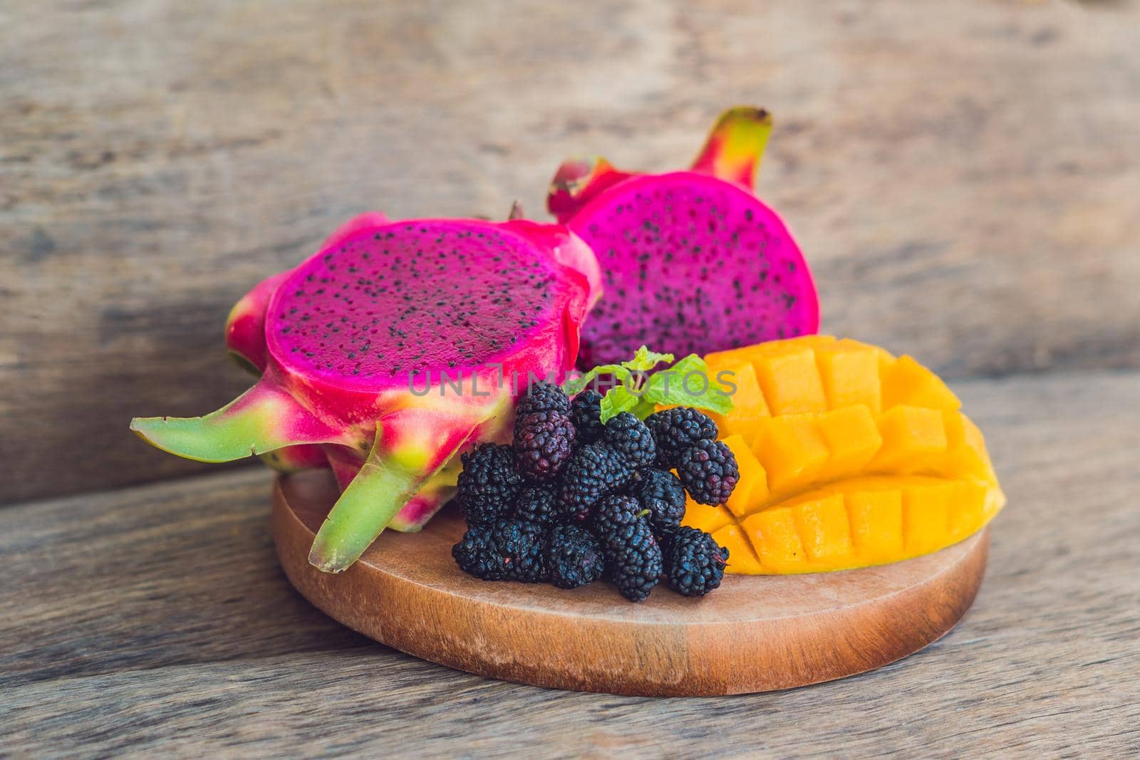 Sliced dragon fruit and mango on an old wooden background.