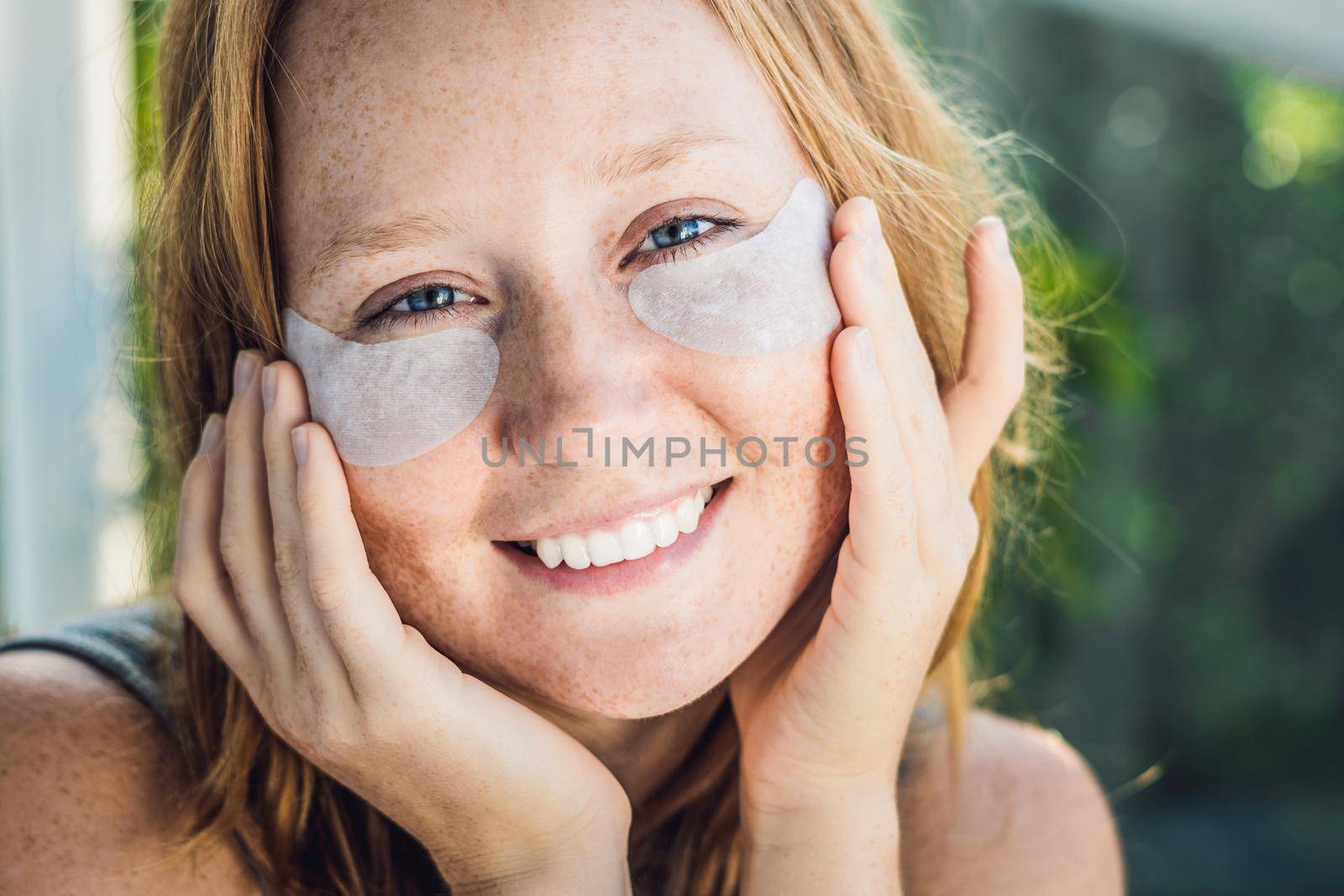 Portrait of Beauty Red-haired woman with eye patches showing an effect of perfect skin. Spa Girl.