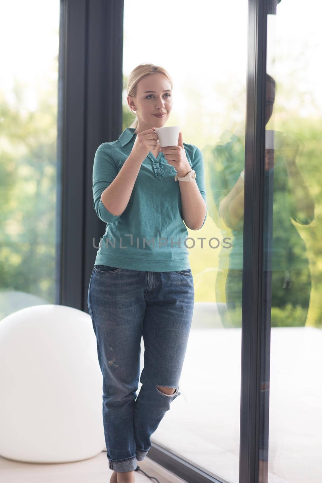 young woman drinking morning coffee by the window by dotshock