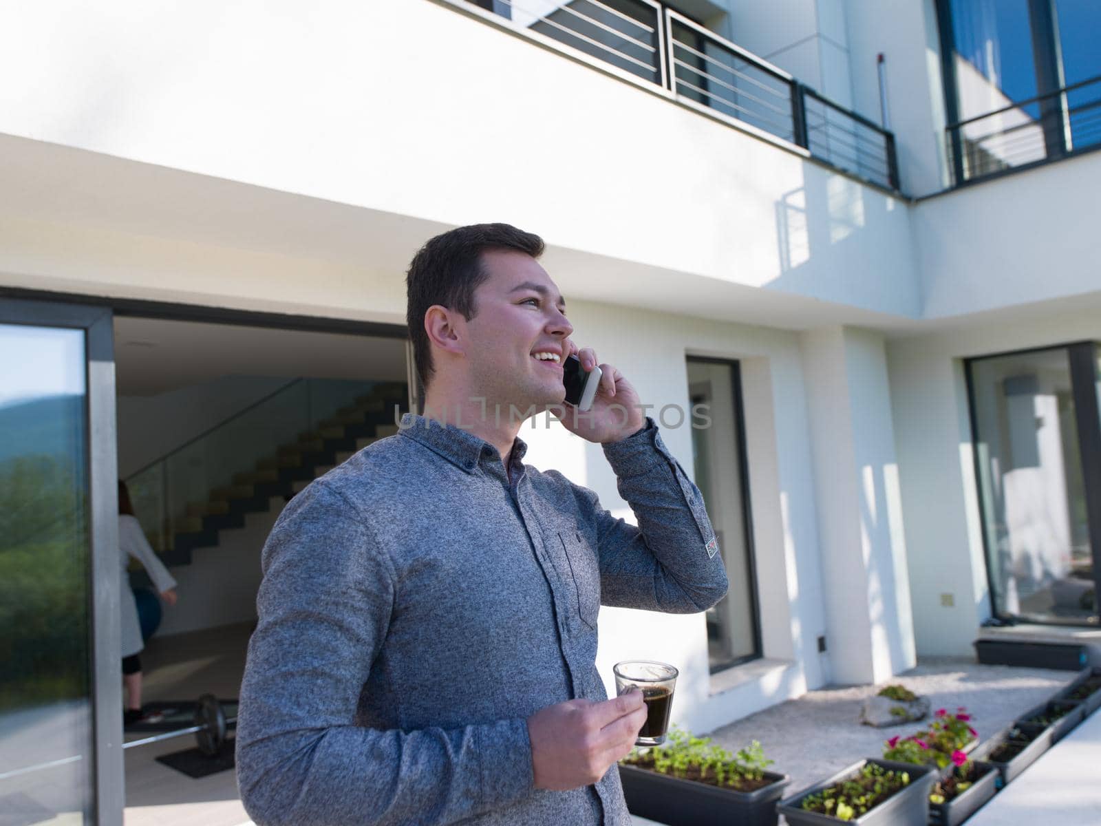 young handsome successful man using mobile phone in front of his luxury home villa