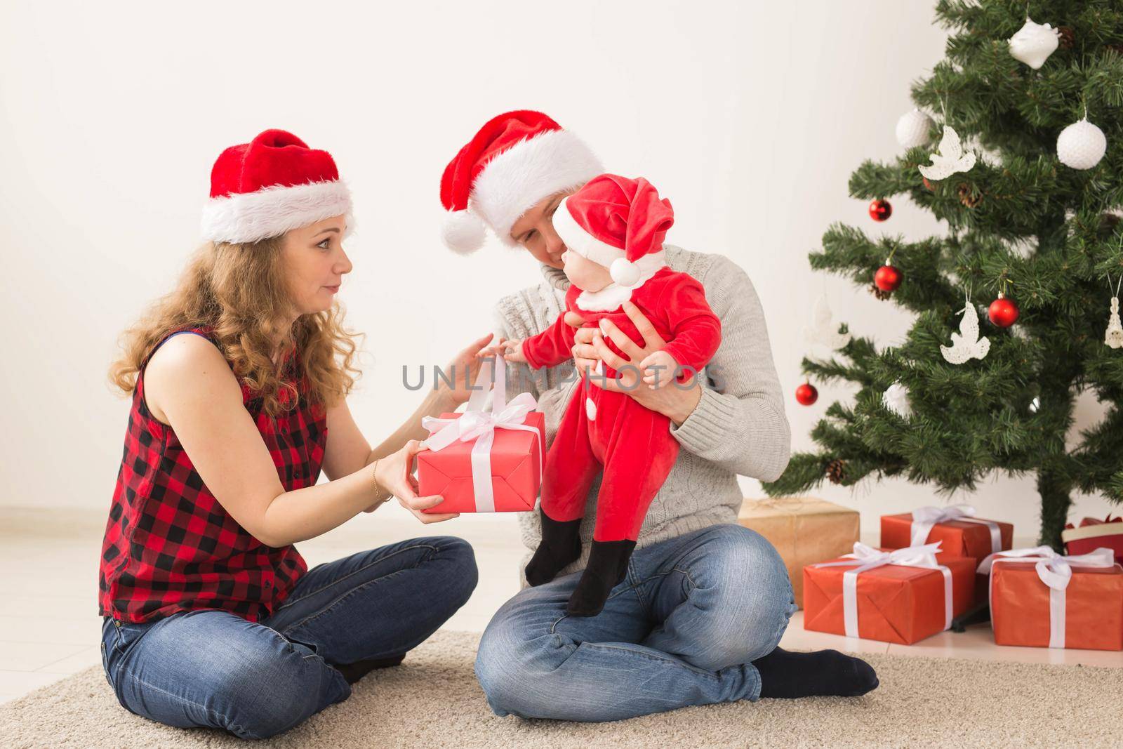 Happy couple with baby celebrating Christmas together at home. by Satura86