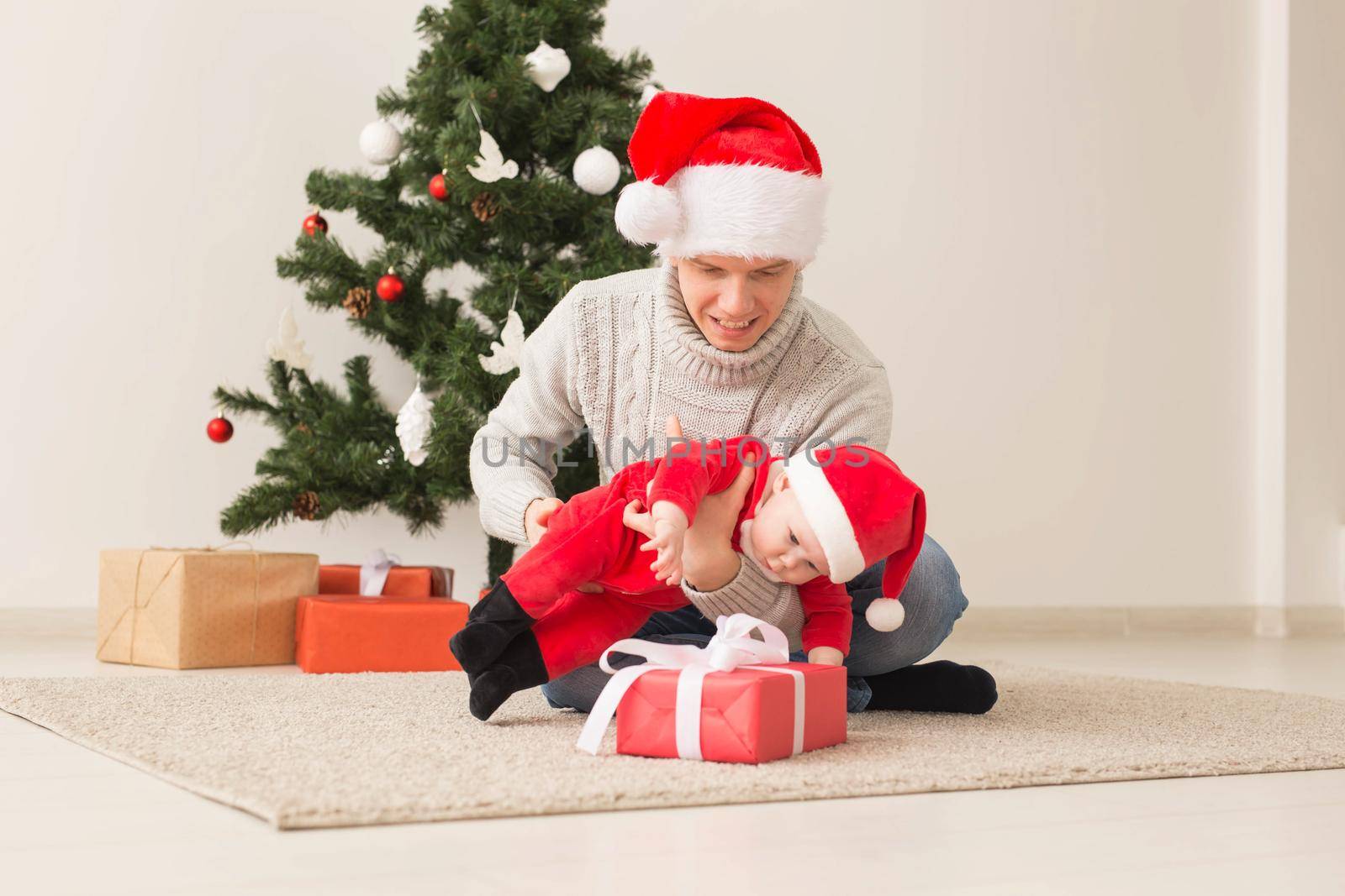 Father with his baby boy wearing Santa hats celebrating Christmas