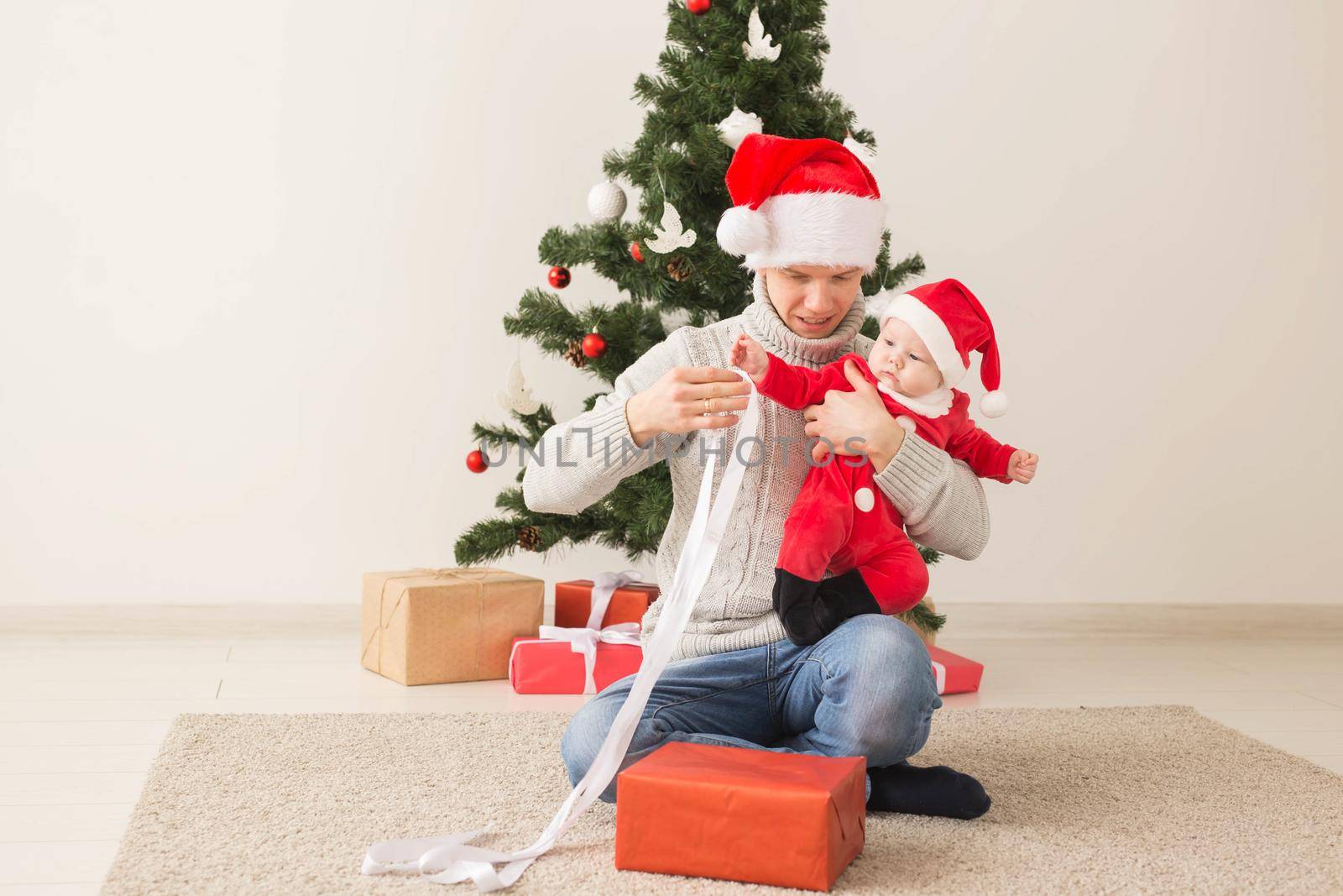 Father with his baby boy wearing Santa hats celebrating Christmas. by Satura86