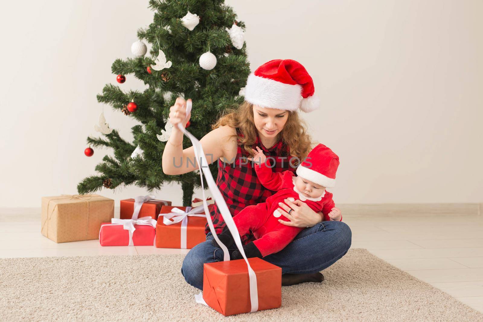 Family, childhood and Christmas concept - Portrait of happy mother and adorable baby in suit of Santa.