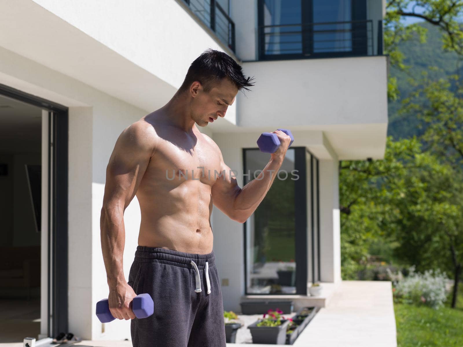 young handsome man doing morning exercises in front of his luxury home villa