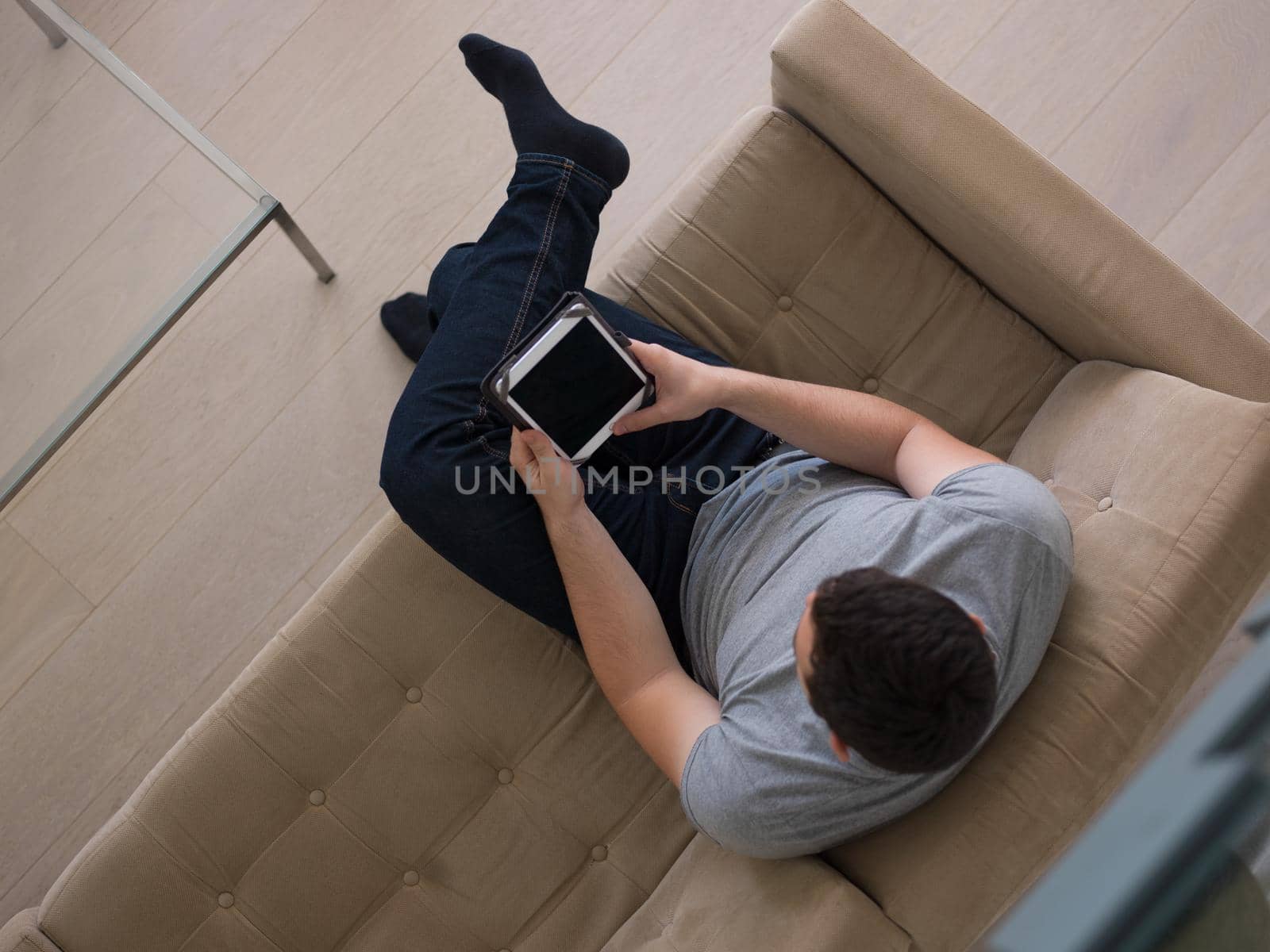 young happy man on sofa using tablet computer at luxury home