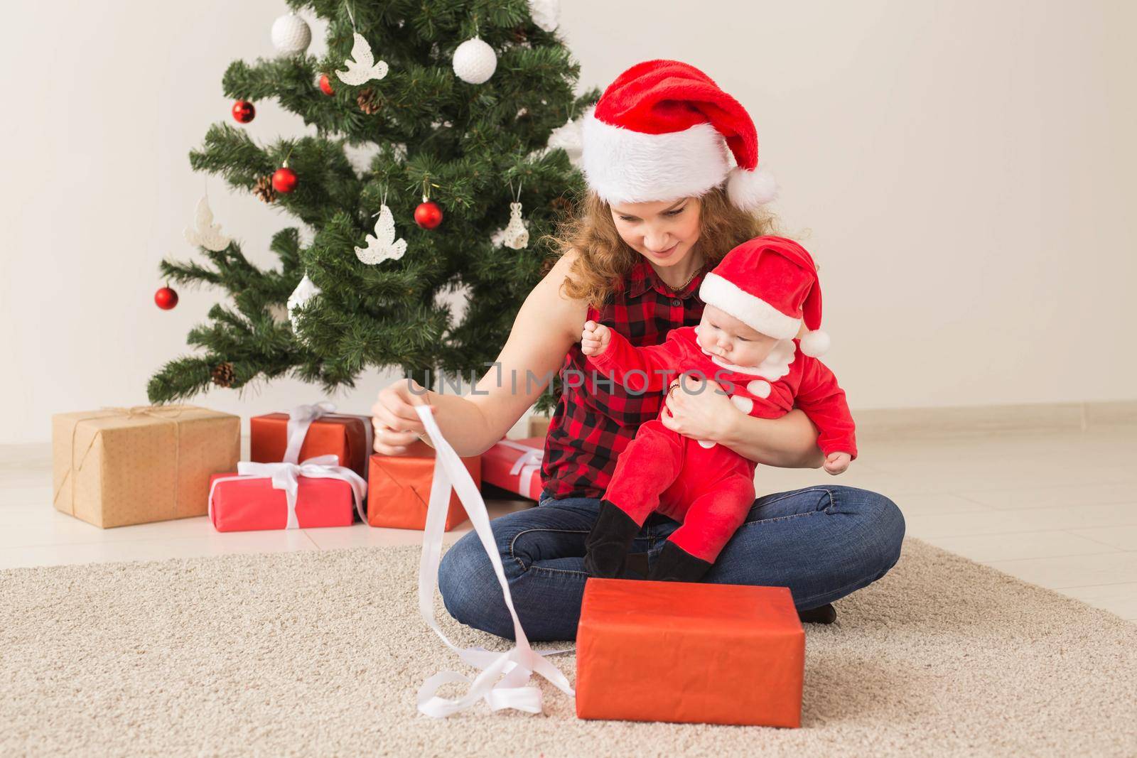 Family, childhood and Christmas concept - Portrait of happy mother and adorable baby in suit of Santa.