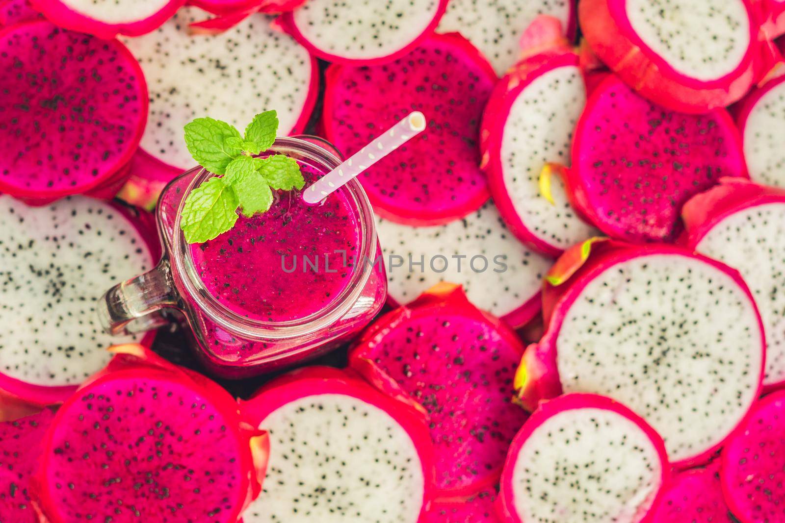 Smoothies of red organic dragon fruit and pieces of dragon fruit on an old wooden background by galitskaya