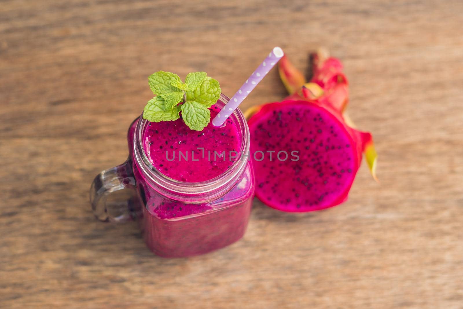 Smoothies of a red organic dragon fruit on an old wooden background by galitskaya